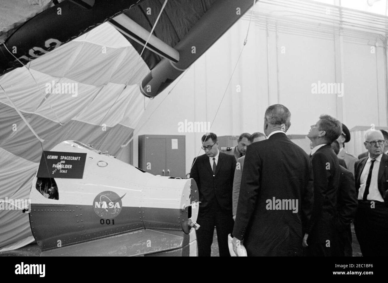 Besichtigung der NASA-Installationen: Houston, Texas, NASA Rich Building, Abfahrt, 11:10am Uhr. Präsident John F. Kennedy sieht ein Modell einer Gemini-Kapsel mit Gleitschirm während einer Tour von Raumfahrzeugen in einem Hangar im Rich Building des bemannten Raumschiffszentrums, Houston, Texas; Vizepräsident Lyndon B. Johnson (zurück zur Kamera) steht links von Präsident Kennedy. Ebenfalls im Bild: Direktor der Verteidigungsforschung und -Technik für das Verteidigungsministerium, Dr. Harold Brown; Naval Aide an den Präsidenten, Kapitän Tazewell T. Shepard, Jr.; Vertreter George P. Miller (Kalifornien). T Stockfoto