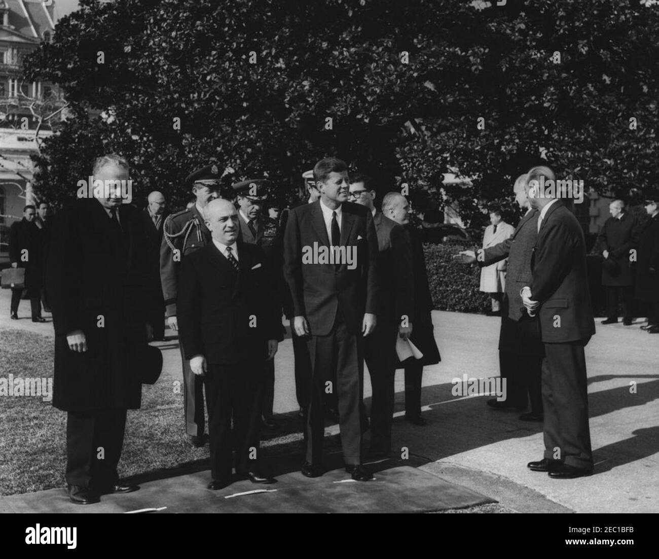 Eintreffen des italienischen Ministerpräsidenten Amintore Fanfani,11:15am Uhr. Präsident John F. Kennedy steht nach der Ankunft des Premierministers Ministeru2019s im Weißen Haus an der Stelle des italienischen Ministerpräsidenten Amintore Fanfani. Von links nach rechts: Unterstaatssekretär George Ball; Premierminister Fanfani; Militärhilfe an den Präsidenten, General Chester V. Clifton (hinter dem Premierminister); Luftwaffenaide an den Präsidenten, Brigadier General Godfrey T. McHugh; Naval Aide an den Präsidenten, Kapitän Tazewell Shepard (hinten, meist versteckt); Präsident Kennedy; Dolmetscher des Außenministeriums, Neil Seidenman (b Stockfoto
