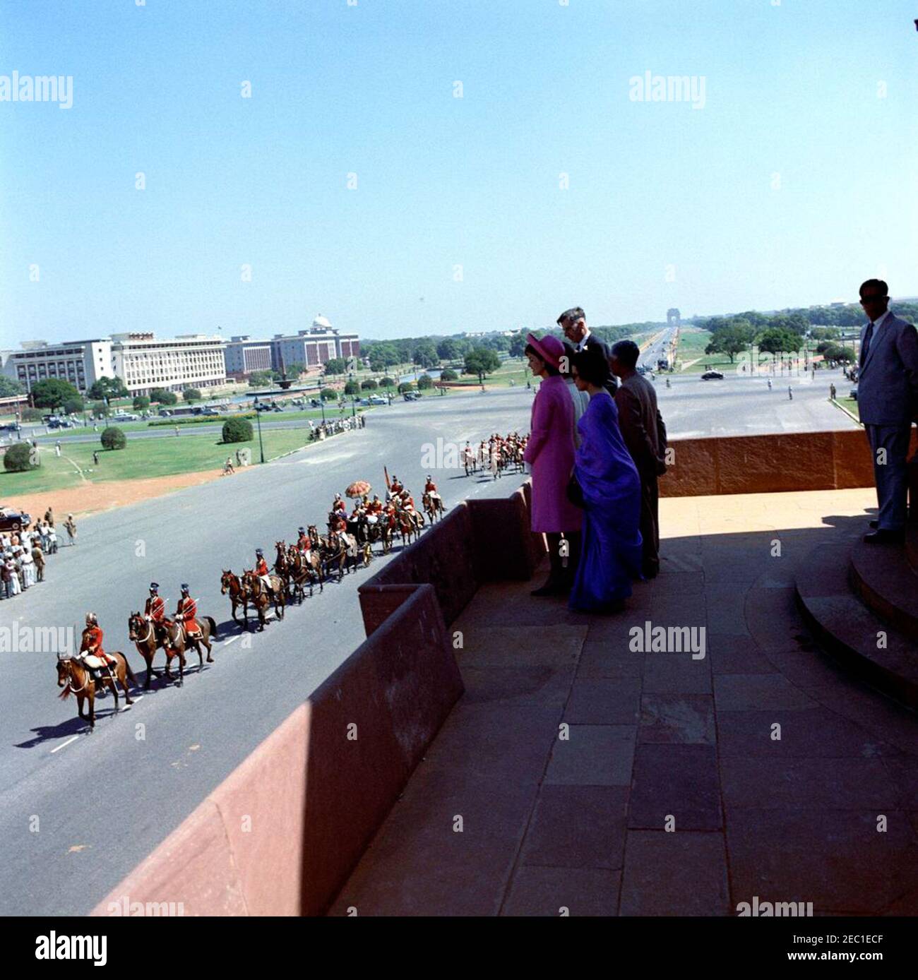 First Lady Jacqueline Kennedyu2019s (JBK) Reise nach Indien und Pakistan: Neu Delhi, Delhi, Indien, Ankunft. Nach ihrer Ankunft in Neu-Delhi, Indien, steht First Lady Jacqueline Kennedy in Vijay Chowk und beobachtet Präsident von Indien Dr. Rajendra Prasadu2019s Autokolonne entlang Rajpath. Mit Frau Kennedy stehen ihre Schwester, Prinzessin Lee Radziwill aus Polen (versteckt), und der Botschafter der Vereinigten Staaten in Indien, John Kenneth Galbraith. Stockfoto