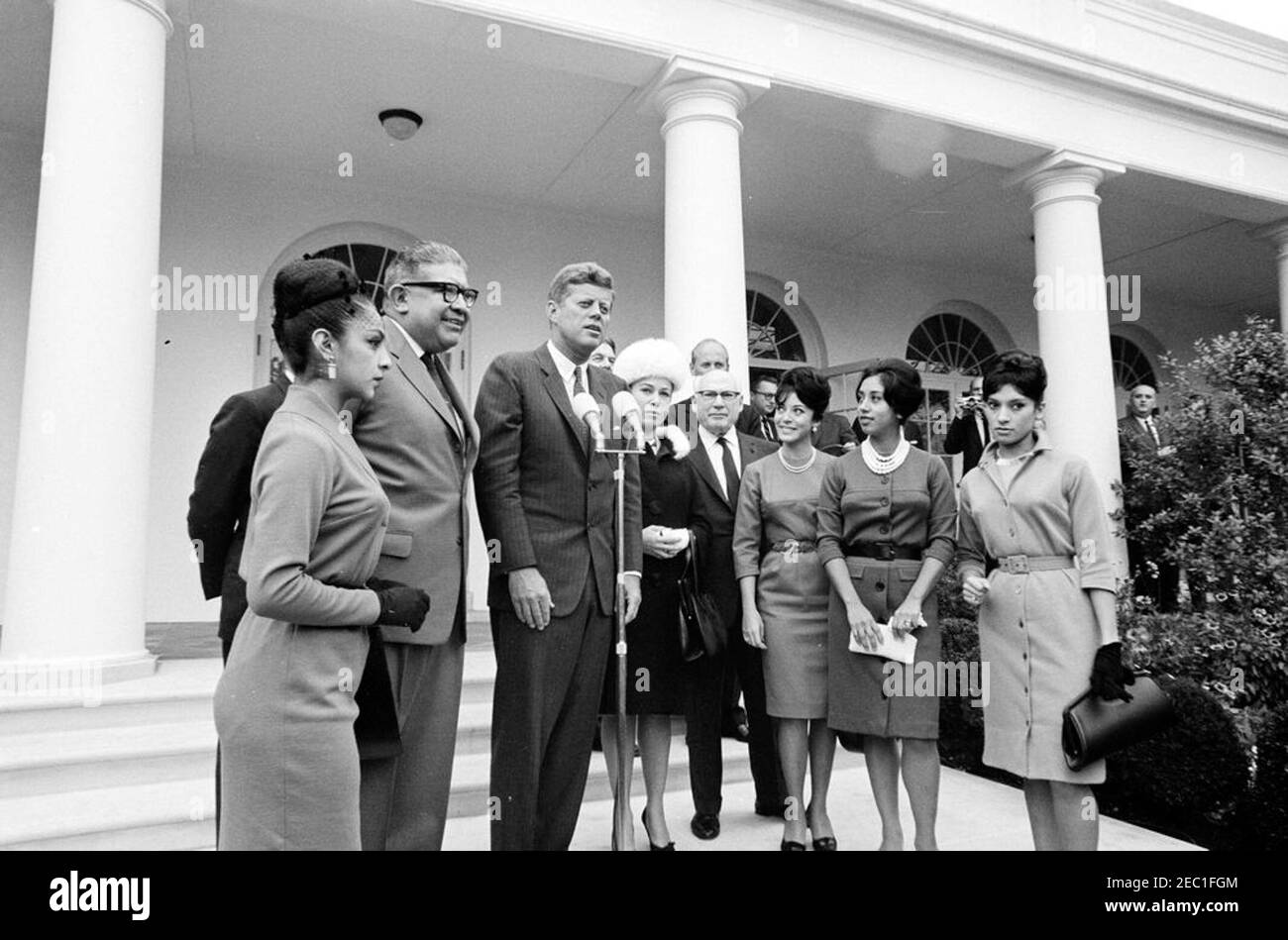 Besuch der Mitglieder des Ballet Folklorico von Mexiko, 12:41pm Uhr. Präsident John F. Kennedy (bei Mikrofonen) spricht Mitglieder des Ballet Folklorico von Mexiko. Ebenfalls im Bild: Dolmetscher des Außenministeriums, Donald Barnes; Botschafter von Mexiko, Antonio Carrillo Flores; Impresario Sol Hurok; stellvertretender Staatssekretär für Inter-amerikanische Angelegenheiten, Edwin M. Martin; Protokollchef, Angier Biddle Duke. Rose Garden, White House, Washington, D.C. Stockfoto
