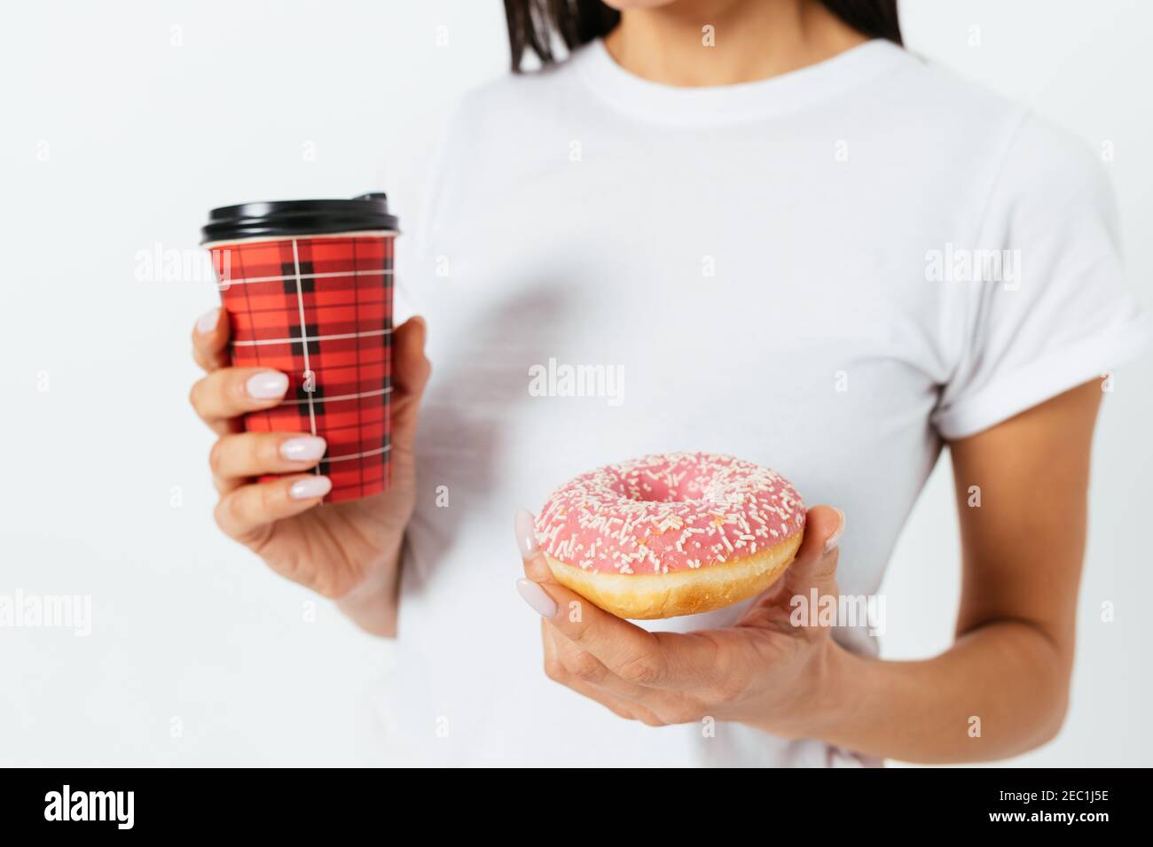 Donut und Pappbecher Kaffee in weiblichen Händen auf weißem Hintergrund Studio, close-up. Stockfoto
