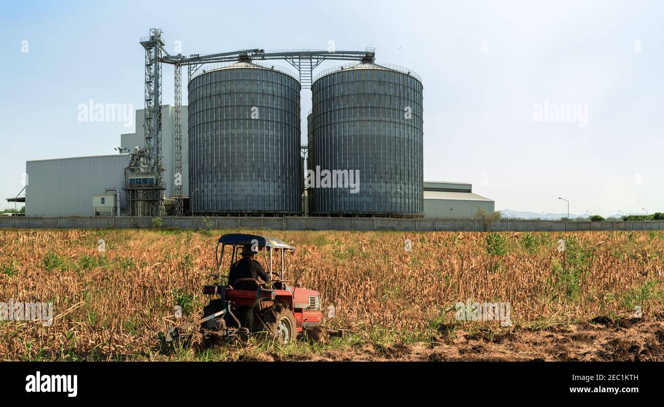 Landwirtschaftliche Silos - Außen, Lagerung und Trocknung von Getreide, Weizen, Mais, Soja, Sonnenblume gegen den blauen Himmel mit landwirtschaftlichen Traktoren in den Vordergrund. Stockfoto