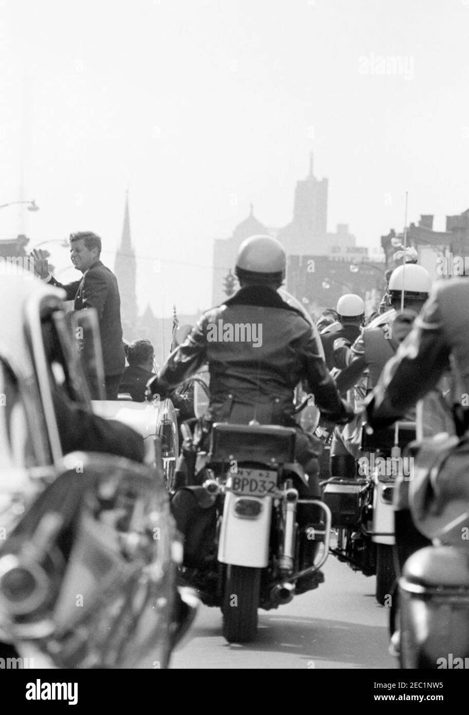 Wahlkampfreise im Kongress: Buffalo, New York, Kundgebung. Präsident John F. Kennedy winkt aus einem Cabrio, während seine Autokolonne während einer Wahlkampfreise durch Buffalo, New York, fährt. Motorradbegleiter reisen neben dem President Kennedyu2019s Auto. Stockfoto
