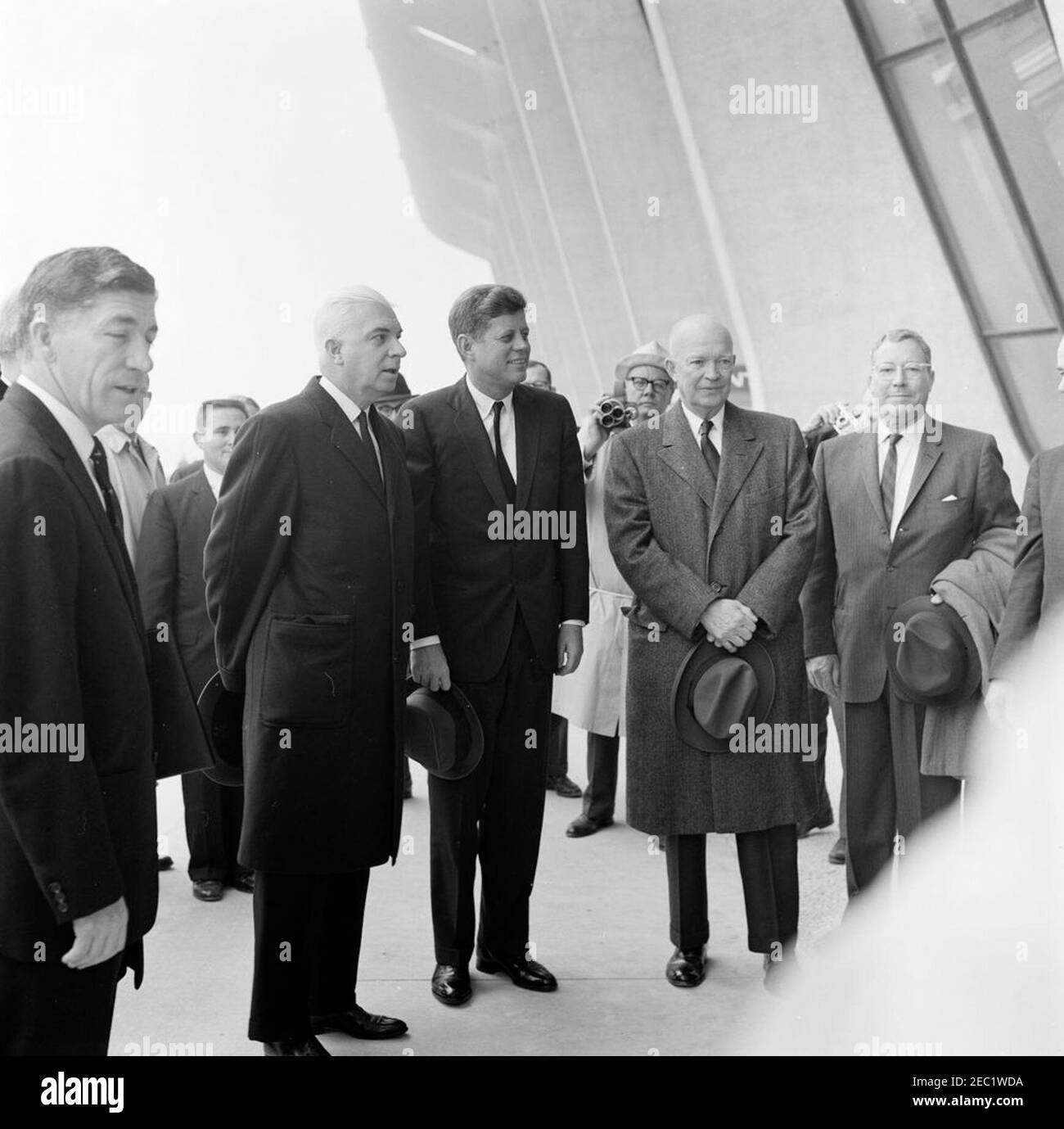 Dedication Ceremonies, Dulles International Airport, 11:12am Uhr. Präsident John F. Kennedy und der ehemalige Präsident, General Dwight D. Eisenhower, nehmen an der Einweihungszeremonie für den internationalen Flughafen Dulles Teil, benannt nach dem verstorbenen Außenminister John Foster Dulles. Von links nach rechts (im Vordergrund): Administrator der Federal Aviation Agency (FAA), Najeeb Halaby; Gouverneur von Virginia, Albertis S. Harrison, Jr.; Präsident Kennedy (Holding hat); General Eisenhower; ehemaliger Administrator der FAA, General Elwood R. u201cPeteu201d Quesada. Chantilly, Virginia. Stockfoto