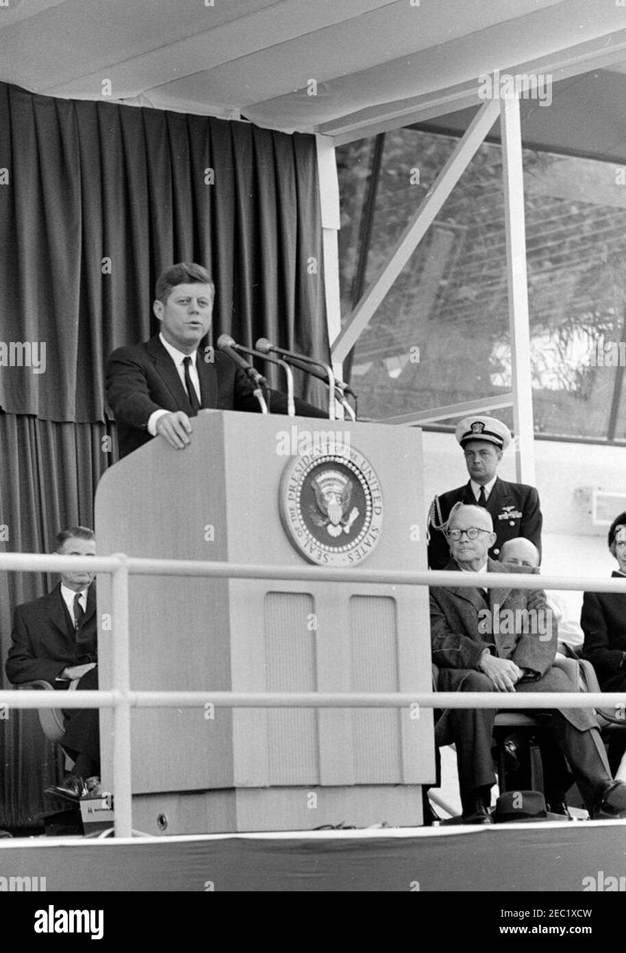 Dedication Ceremonies, Dulles International Airport, 11:12am Uhr. Präsident John F. Kennedy (auf dem Rednerpult) hält Bemerkungen bei der Einweihungszeremonie für den internationalen Flughafen Dulles, benannt nach dem verstorbenen Staatssekretär John Foster Dulles. Auf speakersu2019 Plattform, rechts von Rednerpult (L-R): Ehemaliger Präsident, General Dwight D. Eisenhower; Naval Aide to the President, Captain Tazewell T. Shepard, Jr. (stehend); nicht identifiziert (meist versteckt); Aline B. Saarinen, Witwe des Architekten für den Flughafen, Eero Saarinen (teilweise versteckt am Rand des Rahmens). Vertreter Oren Harris von Arkansas (Gesicht o Stockfoto