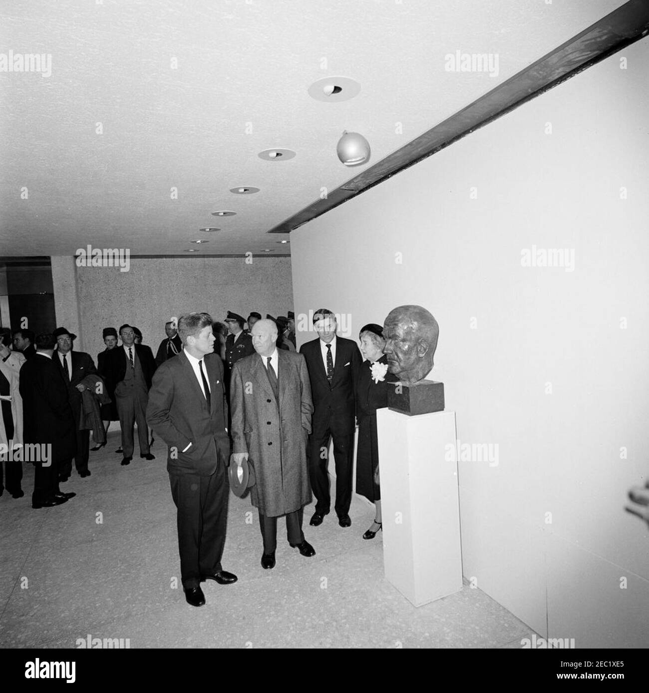Dedication Ceremonies, Dulles International Airport, 11:12am Uhr. Präsident John F. Kennedy und der ehemalige Präsident, General Dwight D. Eisenhower, nehmen an der Einweihungszeremonie für den internationalen Flughafen Dulles Teil, benannt nach dem verstorbenen Außenminister John Foster Dulles. Präsident Kennedy, General Eisenhower (Mitte) und Janet Avery Dulles (Witwe des ehemaligen Sekretärs Dulles) sehen eine Büste des verstorbenen Staatssekretärs; links von Frau Dulles steht der Administrator der Federal Aviation Agency (FAA), Najeeb Halaby. Ebenfalls abgebildet (im Hintergrund): Ehemaliger Administrator der FAA, General Elwood R. u201cP Stockfoto