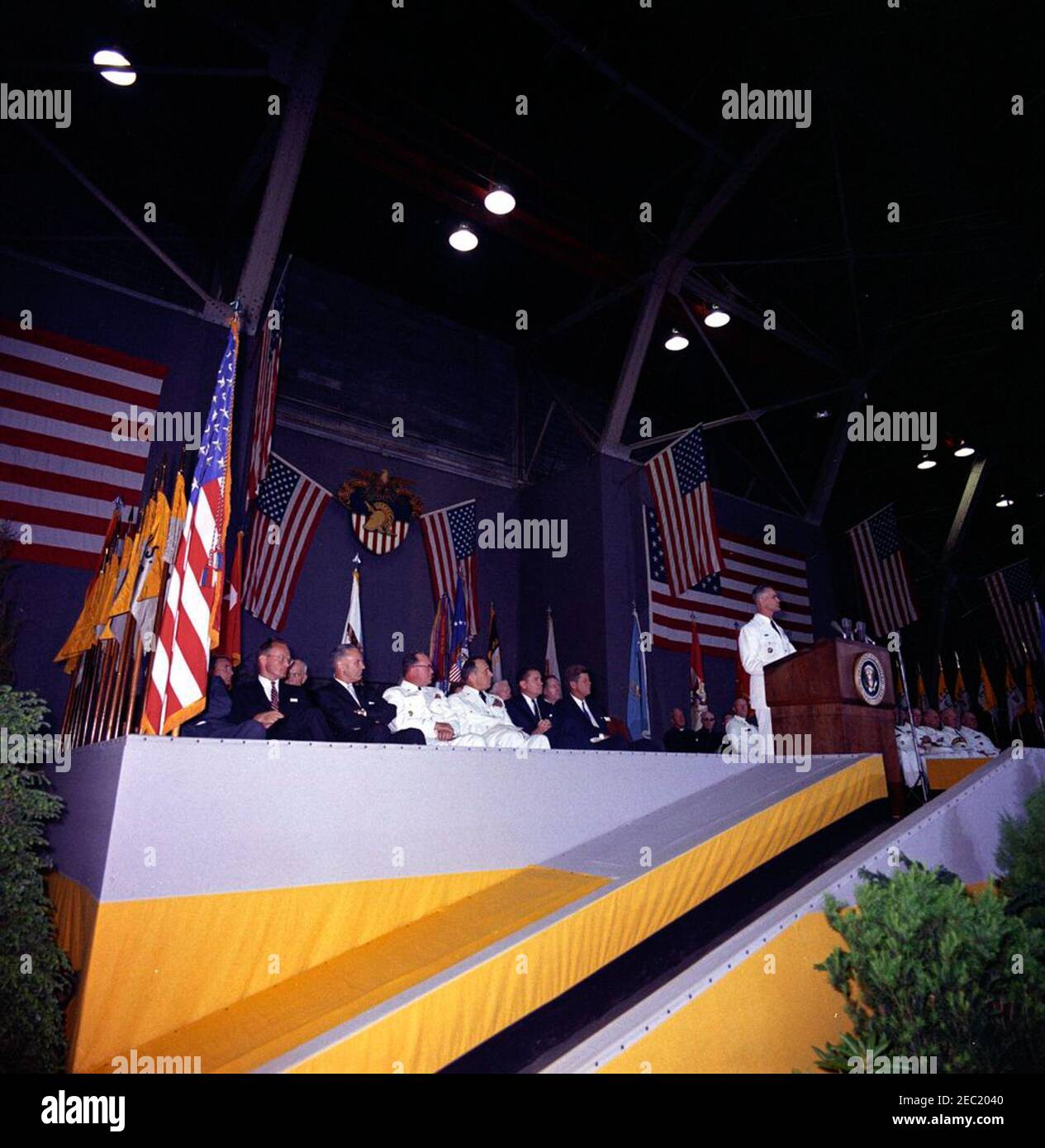Festrede an der United States Military Academy, West Point (New York), 10:01AM Uhr. Der Superintendent der United States Military Academy (USMA), Generalmajor William C. Westmoreland (rechts, am Rednerpult), hält Bemerkungen während der Abschlussübungen an der USMA, West Point, New York. Ebenfalls abgebildet (auf der Bühne sitzend): Sonderassistent des Präsidenten, Kenneth P. Ou2019Donnell (meist verdeckt durch amerikanische Flagge); Sonderassistent des Präsidenten für nationale Sicherheit, McGeorge Bundy; General Maxwell D. Taylor; Stabschef der United States Army, General George H. Decker; Chairman of Stockfoto