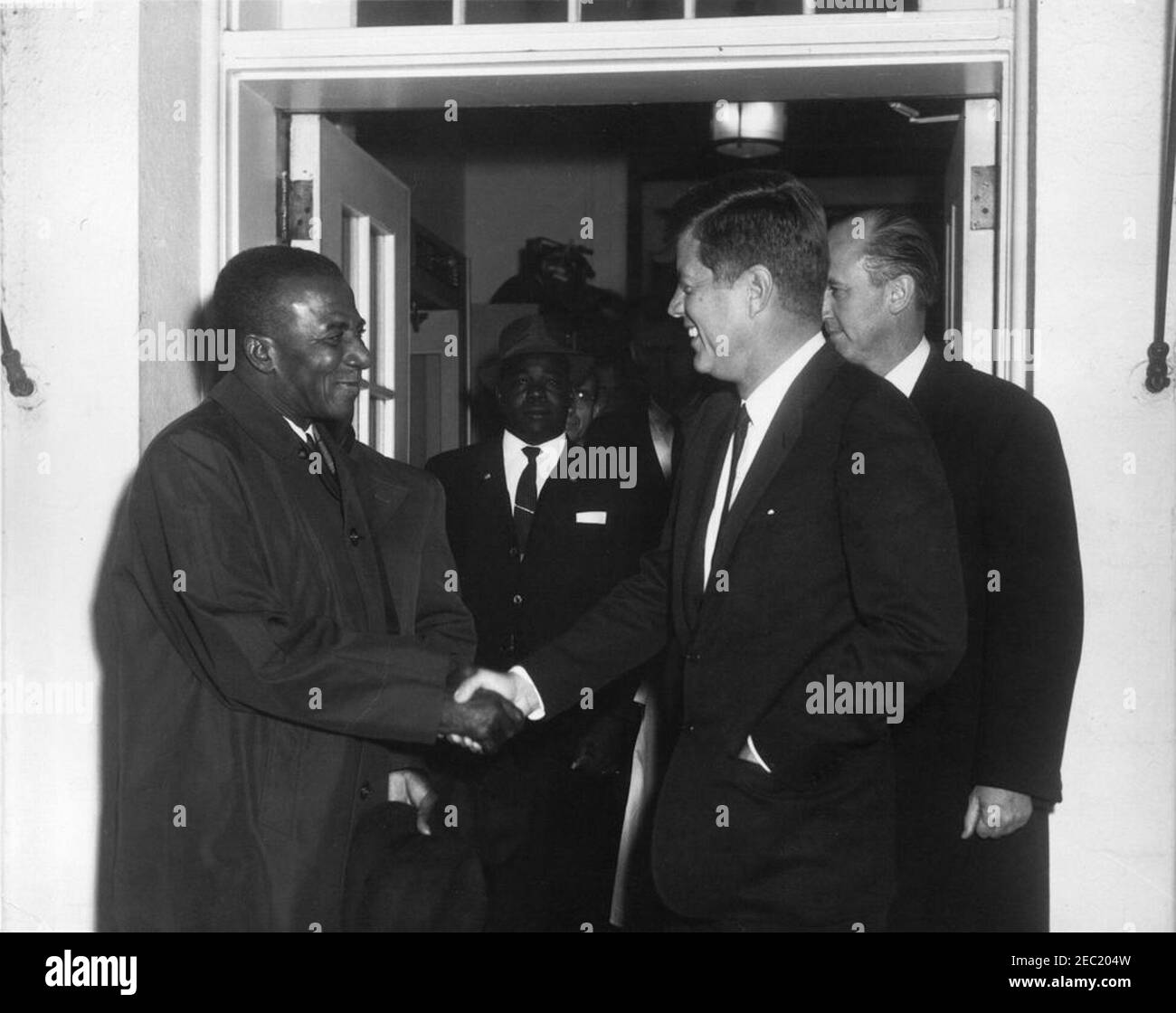 Treffen mit Sylvanus Olympio, Präsident von Togo, 2:53pm Uhr. Präsident John F. Kennedy schüttelt die Hände mit Präsident von Togo, Sylvanus Olympio (links), nach Präsident Olympiou2019s Abreise aus dem Weißen Haus nach einem Treffen und Mittagessen. DER US-Chef des Protokolls, Angier Biddle Duke, steht direkt hinter Präsident Kennedy. Eingang im Westflügel, weißes Haus, Washington, D.C. Stockfoto