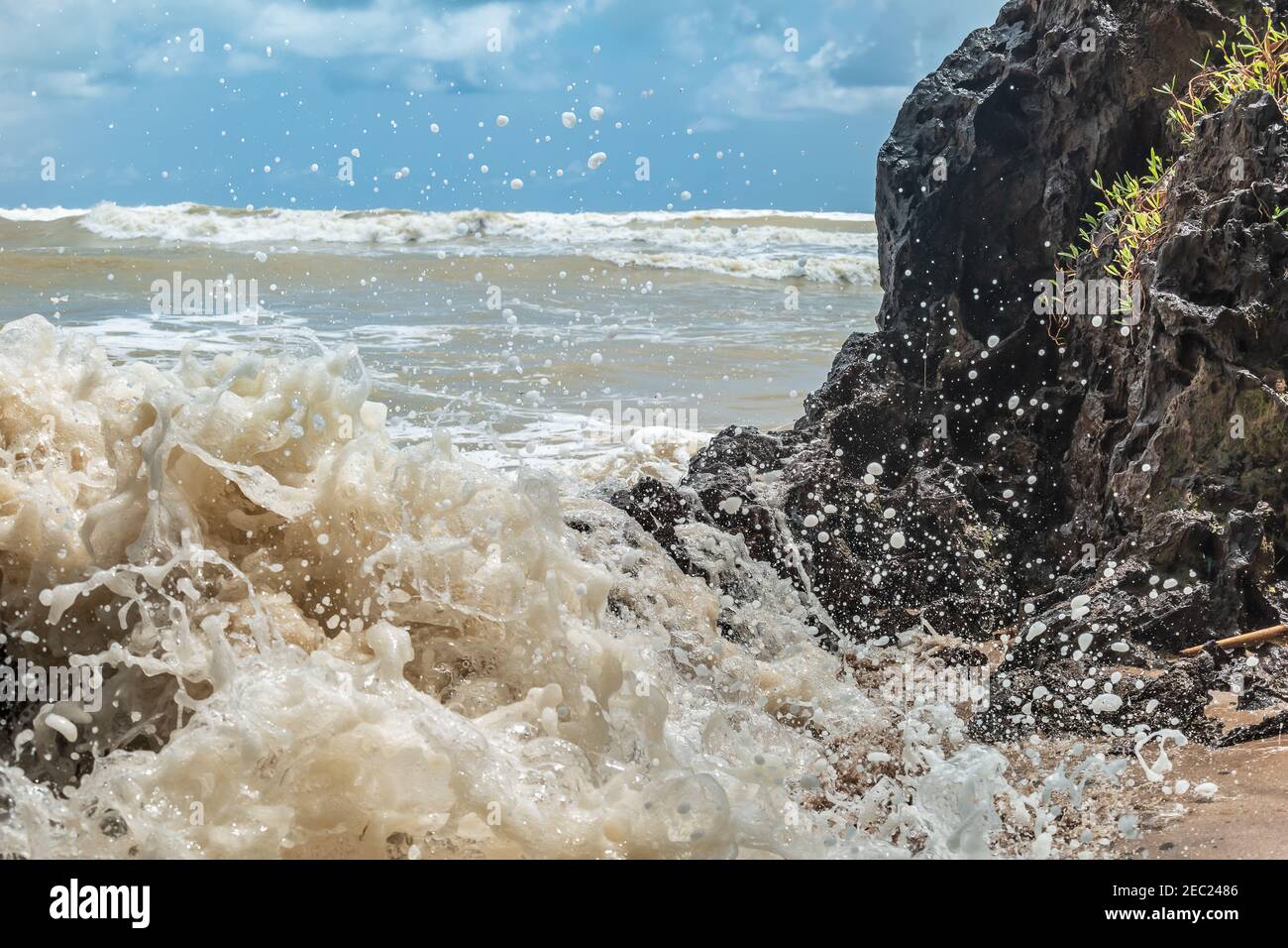 Wellen schlagen dunklen Stein am afrikanischen Strand in Axim Ghana Stockfoto