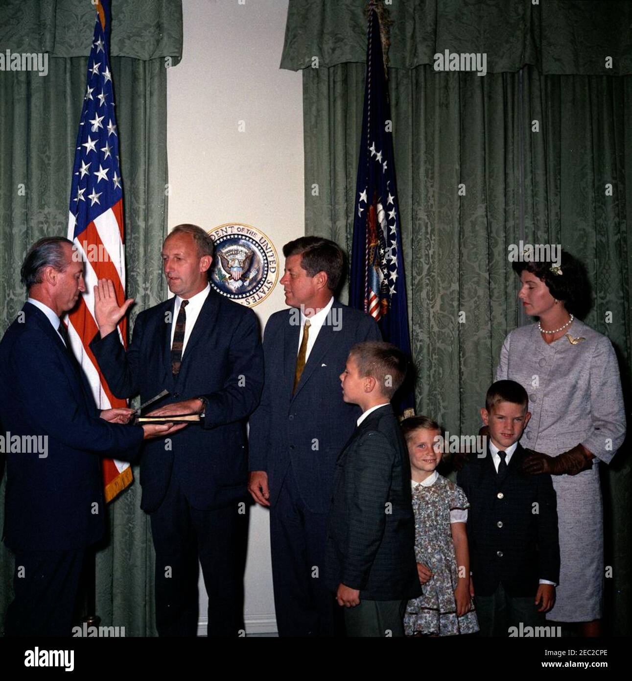 Vereidigung bei der Zeremonie, William Battle, US-Botschafter in Australien, 5:14pm Uhr. Präsident John F. Kennedy sieht sich als Chef des Protokolls, Angier Biddle Duke, verwaltet den Eid an den neu ernannten Botschafter der Vereinigten Staaten in Australien, William C. Battle, während Mr. Battleu0027s Vereidigung-in-Zeremonie. Von links nach rechts: Mr. Duke; Ambassador Battle; President Kennedy; W. Cullen Battle, Jr.; Janie Battle; Robert W. Battle; Barry Webb Battle. Cabinet Room, White House, Washington, D.C. Stockfoto