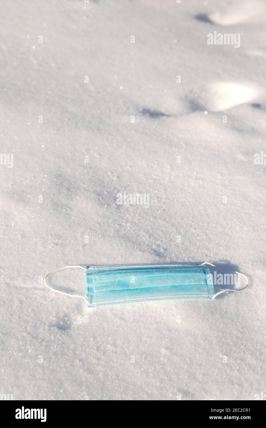 Schützende blaue medizinische Maske für Virus liegt im Schnee, Covid-19, Pandemie, Winter, Virus, Gesundheitskonzept, Kopierraum Hintergrund Stockfoto