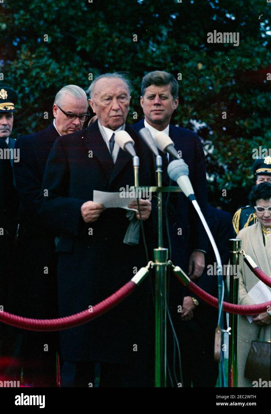 Ankunftszeremonie für Konrad Adenauer, Bundeskanzler der Bundesrepublik Deutschland, 10:45am Uhr. Präsident John F. Kennedy sieht sich als Bundeskanzler der Bundesrepublik Deutschland, Dr. Konrad Adenauer, hält Bemerkungen während der Ankunftszeremonie zu seinen Ehren. Ebenfalls im Bild: Vorsitzender der Generalstabschefs, General Maxwell D. Taylor; Botschafter der Bundesrepublik Deutschland, Karl Heinrich Knappstein; stellvertretender Leiter der Sprachdienste im Außenministerium, Dolmetscherin Nora Lejins; Militärhilfe an den Präsidenten, General Chester V. Clifton. South Lawn, White House, Washington, D.C. Stockfoto