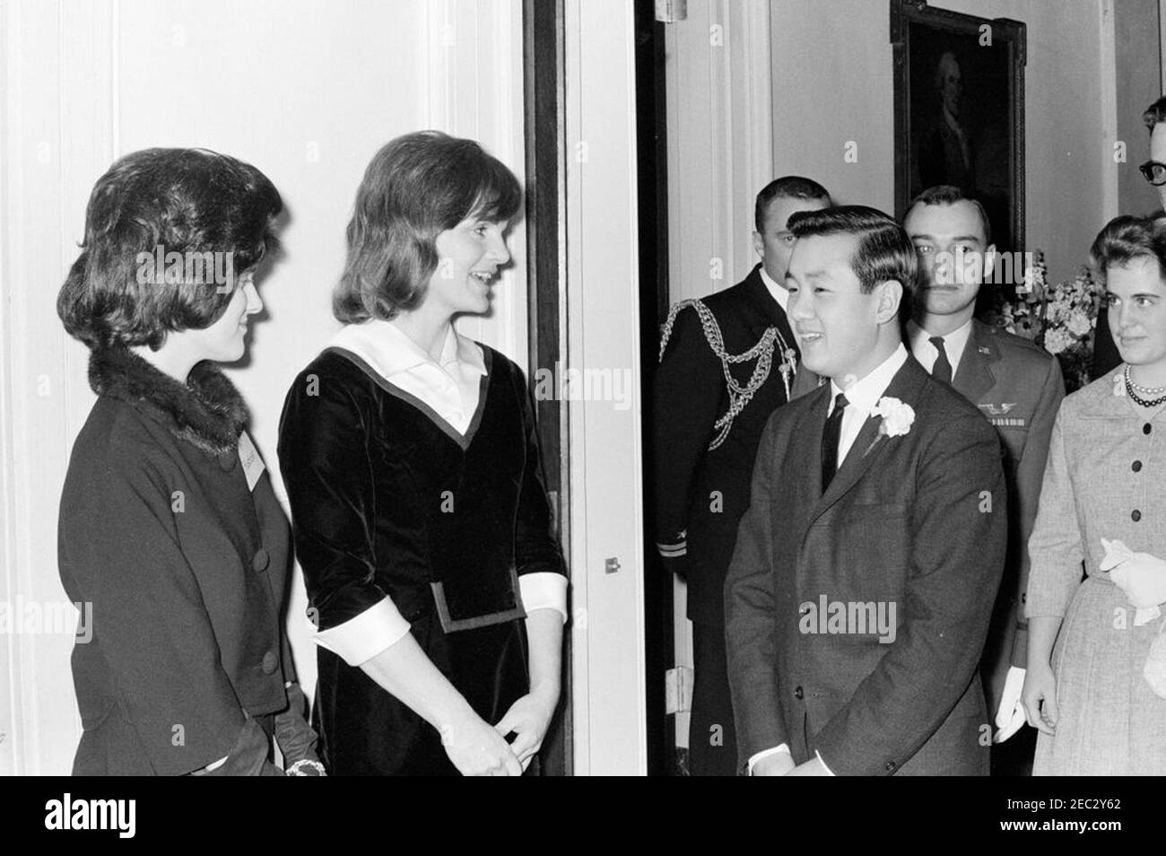 First Lady Jacqueline Kennedyu0027s (JBK) Musikprogramm für Jugendliche. First Lady Jacqueline Kennedy (Mitte) und Lucy Baines Johnson (ganz links) begrüßen den koreanischen Pianisten Tong-il Han nach seinem Auftritt im Weißen Haus; Herr Han trat im Rahmen der fünften Ausgabe von Mrs. Kennedyu0027s Musical Programs for Youth by Youth auf. Die First Lady hielt die Veranstaltung für die Kinder von Botschaftern, Kabinettsmitgliedern und Beamten des Außenministeriums, die in Washington, D.C., im Staatlichen Speisesaal des Weißen Hauses, Washington, D.C., leben Stockfoto