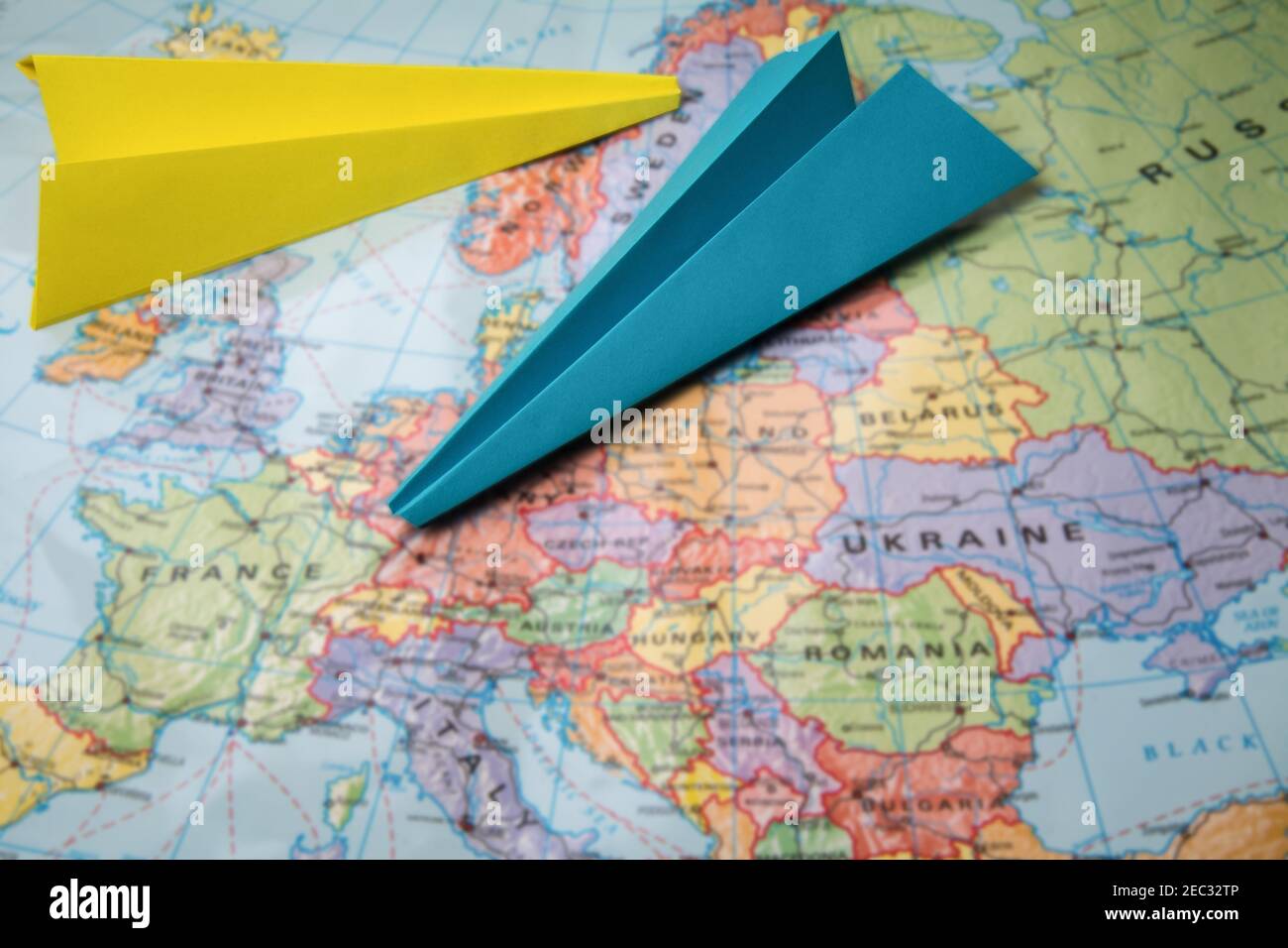 Zwei fliegende Papierflieger über verschwommenem Kartenhintergrund. Flugzeug als Symbol für Reisen und Tourismus Stockfoto