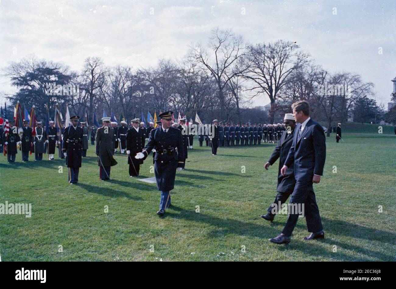 Ankunftszeremonie für Abdirashid Ali Shermarke, Premierminister der somalischen Republik, 11:45am Uhr. Präsident John F. Kennedy geht mit dem Premierminister der somalischen Republik, Dr. Abdirashid Ali Shermarke, während der Ankunftszeremonien zu Ehren von Premierminister Shermarke; ein nicht identifizierter Kommandant der Truppen geht links von Präsident Kennedy und dem Premierminister. Militärische Farbe und Ehre Garde Truppen stehen auf die Aufmerksamkeit im Hintergrund. South Lawn, White House, Washington, D.C. [Makel auf dem Bild sind original auf das Negative.] Stockfoto