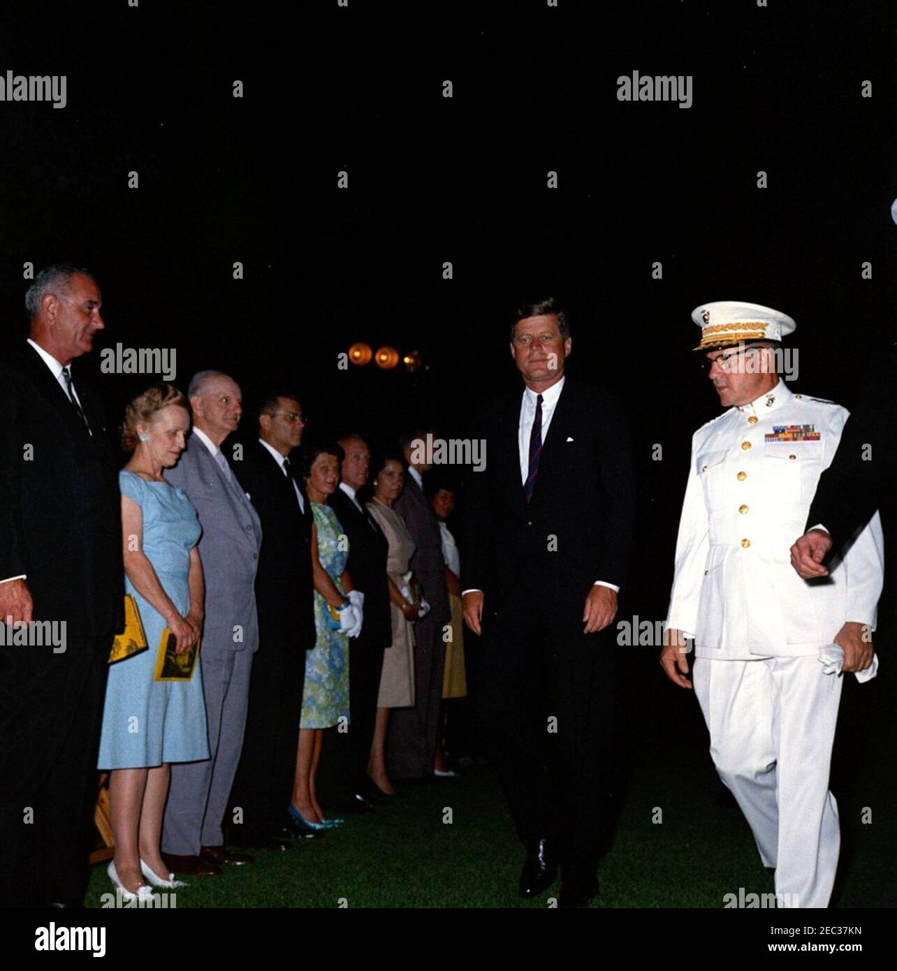 Präsident Kennedy blickt auf die Marine Corpsu0027 Evening Parade, in den Marine Barracks Washington, D.C. (8th u0026 I Streets, SE), 9:00pm Uhr. Präsident John F. Kennedy nimmt an einer Abendparade in den Marine Barracks Teil (8.U201c8.u0026 Iu201d) in Washington, D.C., Kommandant des United States Marine Corps, General David M. Shoup, geht nach rechts. Links stehend (L-R): Vizepräsident Lyndon B. Johnson; Zola Shoup; Kongressabgeordneter Carl Vinson (Georgia); Verteidigungsminister Robert S. McNamara; Margaret Craig McNamara; Generalpostmeister, J. Edward Day; Mary Louise Day; Direktor des Büros der Stockfoto