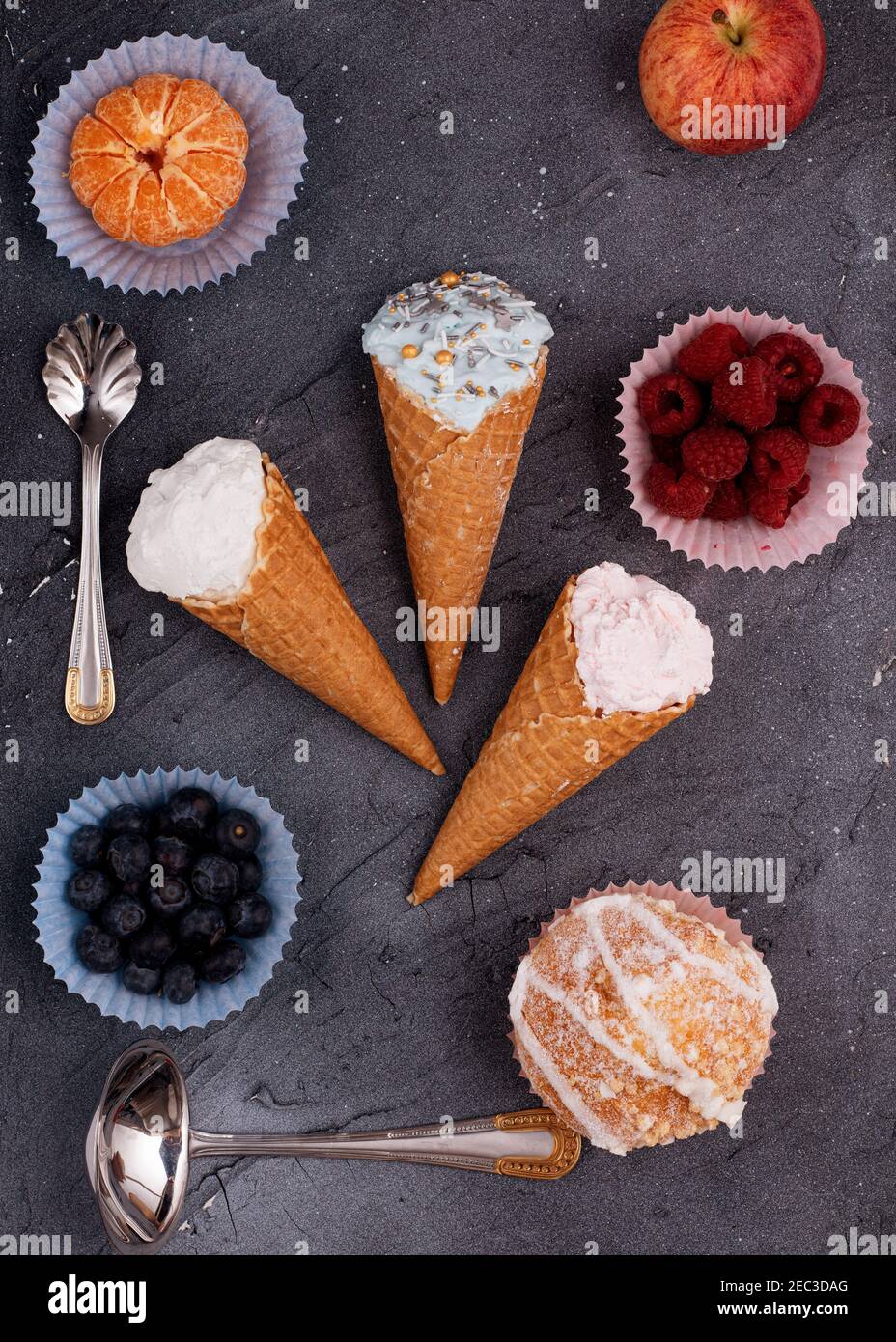 Drei Eis, Himbeere, Heidelbeere, Muffin, Apfel, Und Mandarine auf grauem Hintergrund. Blick von oben. Stockfoto