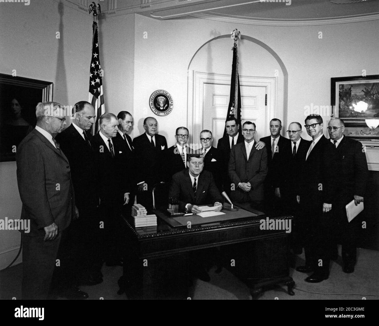 Bill Signing - H.R. 4997 Feed Grain Act, 12:35pm. Präsident John F. Kennedy (sitzt an der Rezeption) hält Bemerkungen zur Unterzeichnung des Feed Grain Act von 1963. Stehend (von links nach rechts): Stellvertretender Landwirtschaftsminister, John P. Duncan, Jr.; Vertreter Graham Purcell (Texas); Vertreter W. R. Poage (Texas); Senator Olin D. Johnston (South Carolina); Vertreter Harold D. Cooley (North Carolina); Senator Allen J. Ellender (Louisiana); Vertreter Paul C. Jones (Missouri); Präsident der National Farmers Organization, Oren Lee Staley; Glen J. Talbott von der National Farmers Union; Stockfoto