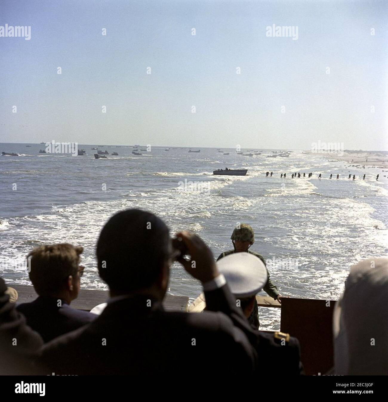 Besuch der Atlantikflotte: Präsident Kennedy sieht die Übungen des Marine Corps im Bogue Field und Onslow Beach, Camp Lejeune, North Carolina, 2:11pm Uhr. Präsident John F. Kennedy (unten links, zurück zur Kamera, mit Sonnenbrille) sieht sich eine Demonstration der amphibischen Landeoperationen der US-Marine und des Marine Corps am Onslow Beach vom Riseley Pier, Camp Lejeune, North Carolina, an. Stockfoto