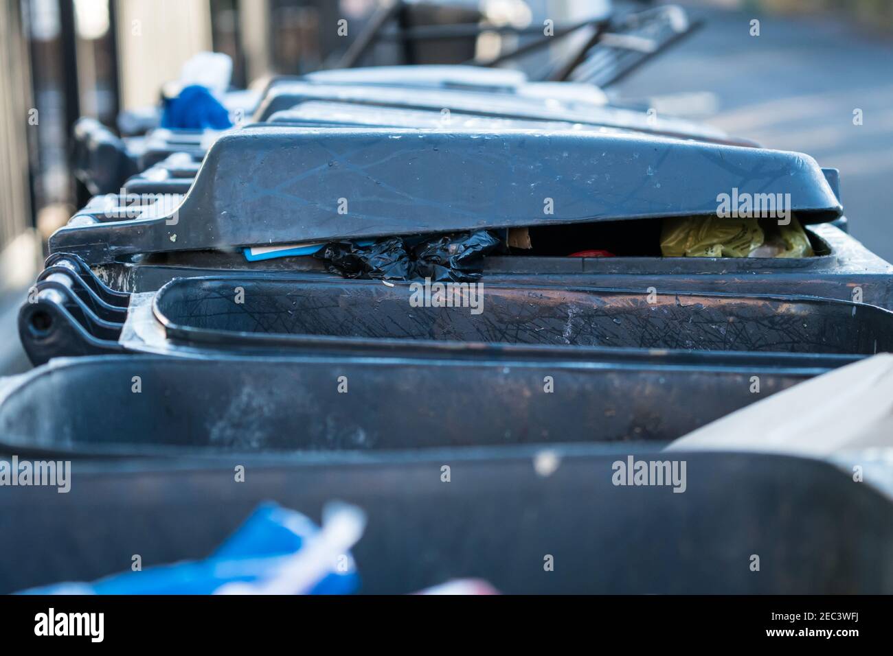 Schwarze Mülltonnen, Mülltonnen, Mülltonnen mit Müll in einer Reihe warten auf Sammlung Konzept Abfall und kommunalen Dienstleistungen gefüllt Stockfoto