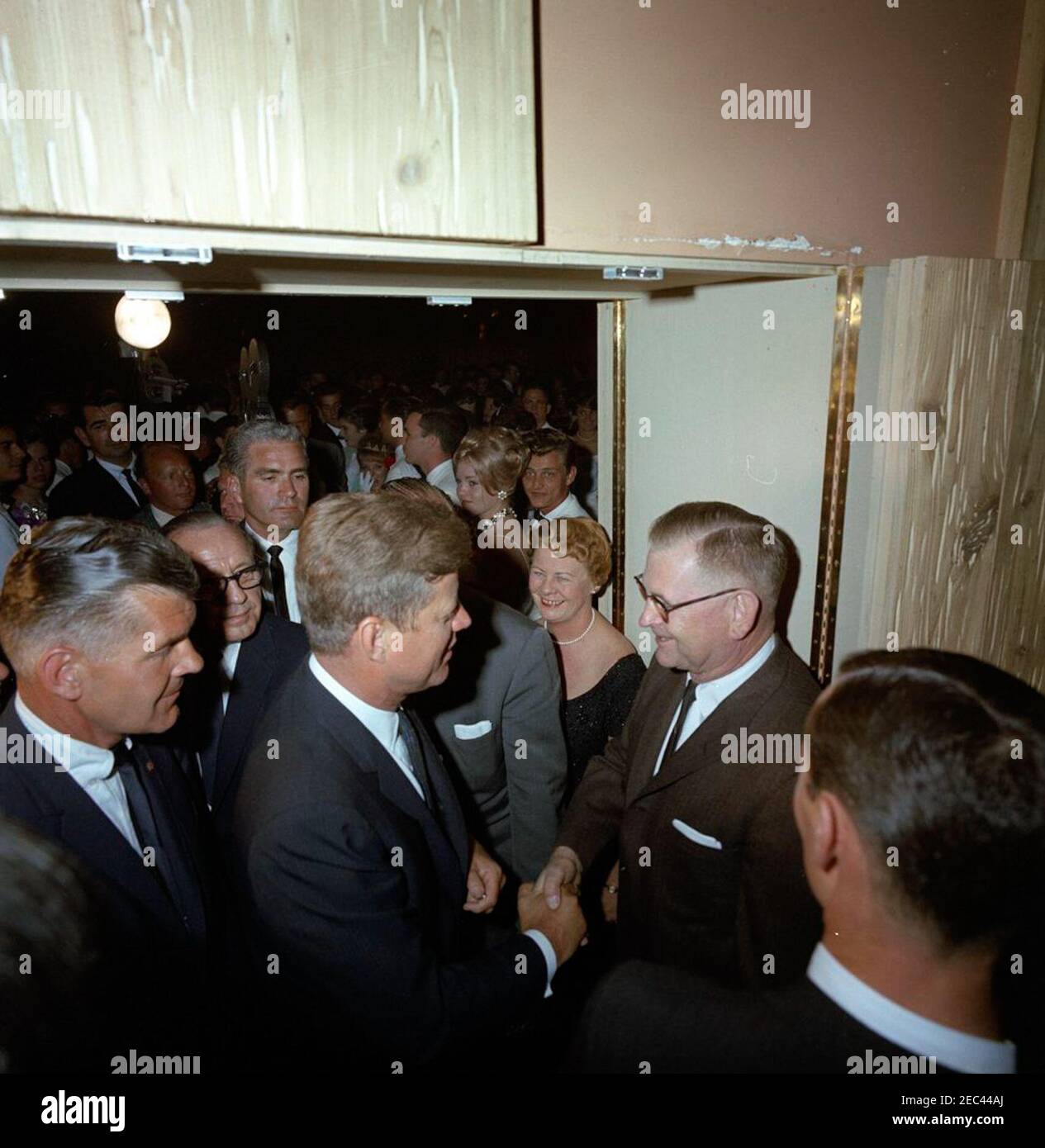 Reise in die westlichen Staaten: Los Angeles, Kalifornien, Beverly Hilton Hotel, Präsident Kennedy und Jack Benny besuchen die John Burroughs High School Senior Prom, 10:22pm. Präsident John F. Kennedy (links unten) schüttelt sich bei einem Besuch des Abschlussballs der John Burroughs High School in Burbank, Kalifornien, die Hände mit einem unbekannten Mann im Grand Ballroom des Beverly Hilton Hotels, Los Angeles, Kalifornien. Präsident Kennedy und Komiker Jack Benny (hinter dem Präsidenten stehend, mit Brille) besuchten den Tanz, nachdem sie an einem Spendenessen im selben Hotel teilgenommen hatten; ebenfalls im Bild: Weißes Haus Stockfoto