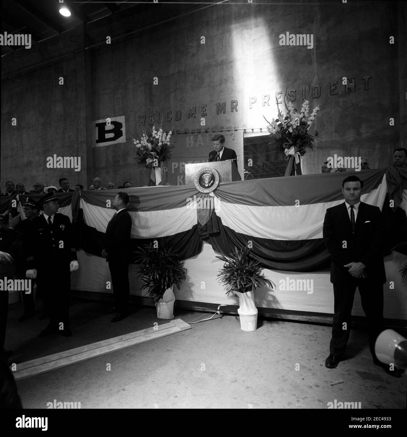 Ausflug nach Louisiana und Florida: New Orleans, Louisiana, Adresse Nashville Avenue Wharf Widmung, 10:30am. Präsident John F. Kennedy (hinter einem Rednerpult in der Mitte) hält Bemerkungen bei der Einweihungszeremonie für Nashville Avenue Wharf, einem neuen Hafenterminal am Hafen von New Orleans in New Orleans, Louisiana. Zu den auf der Bühne sitzenden Personen gehören: Kongressabgeordneter Hale Boggs (Louisiana); Militärhilfe für den Präsidenten, General Chester V. Clifton; Gouverneur von Louisiana, James u201cJimmieu201d Davis. Der Geheimagent des Weißen Hauses, Charlie Kunkel, steht ganz rechts. [Foto von Harold Sellers] Stockfoto