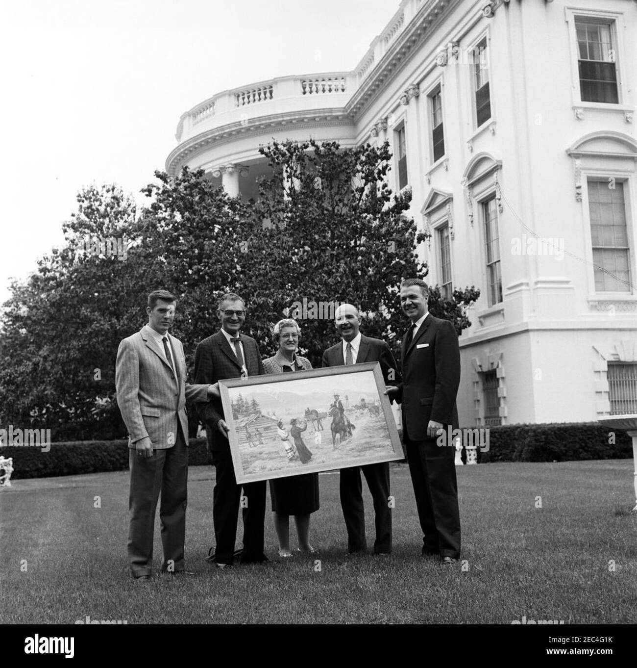 Präsentation eines Gemäldes, die Reise nach Westen endet, für Präsident Kennedy (Präsidentenassistent David F. Powers). Sonderassistent des Präsidenten, Dave Powers (zweiter von rechts), erhält ein Gemälde, u201cThe westwärts Reise endet,u201d im Namen von Präsident John F. Kennedy. Ganz rechts steht der Vertreter Arnold Olsen (Montana), alle anderen sind nicht identifiziert. East Wing Lawn, White House, Washington, D.C. Stockfoto