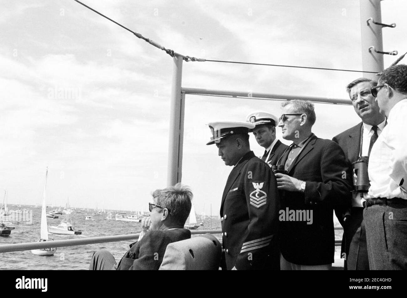 Präsident Kennedy beobachtet das 1st Americau0027s Cup Race. Präsident John F. Kennedy (mit Sonnenbrille) beobachtet das erste Rennen des Cup 1962 Americau0027s von an Bord der USS Joseph P. Kennedy, Jr. Links nach rechts: Präsident Kennedy; nicht identifizierter Offizier; Naval Aide an den Präsidenten, Kapitän Tazewell Shepard; Untersekretär der Marine, Paul u0022Redu0022 Fay; Franklin D. Roosevelt, Jr.; Assistant Secretary of the Treasury, James A. Reed. Newport, Rhode Island. Stockfoto