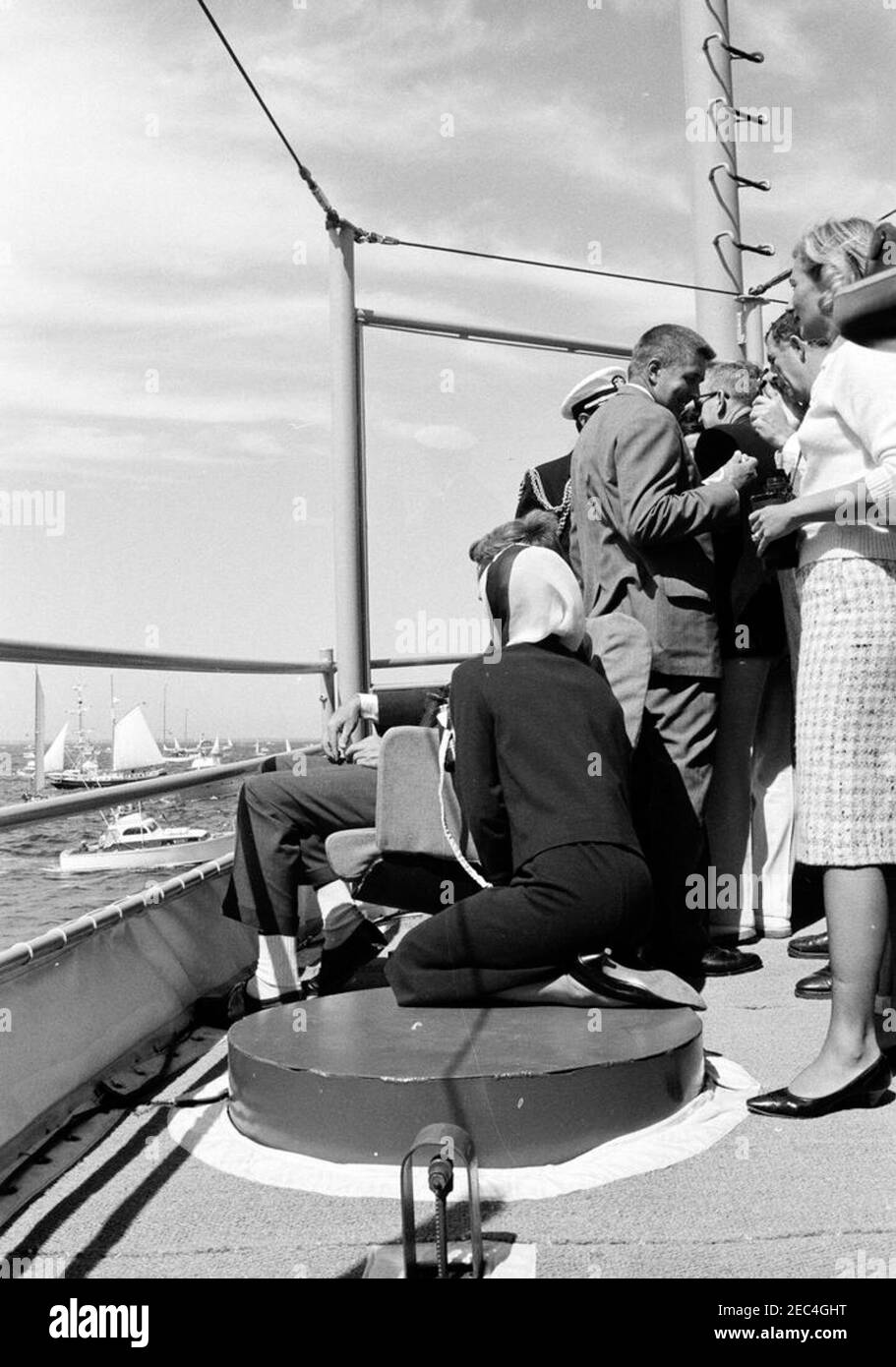 Präsident Kennedy beobachtet das 1st Americau0027s Cup Race. Präsident John F. Kennedy und First Lady Jacqueline Kennedy (beide in der Mitte sitzend) beobachten das erste Rennen des Cup 1962 Americau0027s von Bord der USS Joseph P. Kennedy, Jr., vor der Küste von Newport, Rhode Island. Ebenfalls im Bild: Naval Aide to the President, Captain Tazewell Shepard; Senator Benjamin A. Smith II (Massachusetts); Untersekretär der Marine, Paul u0022Redu0022 Fay; Assistant Secretary of the Treasury, James A. Reed; Nuala Pell (Ehefrau von Senator Claiborne Pell von Rhode Island). Newport, Rhode Island. Stockfoto