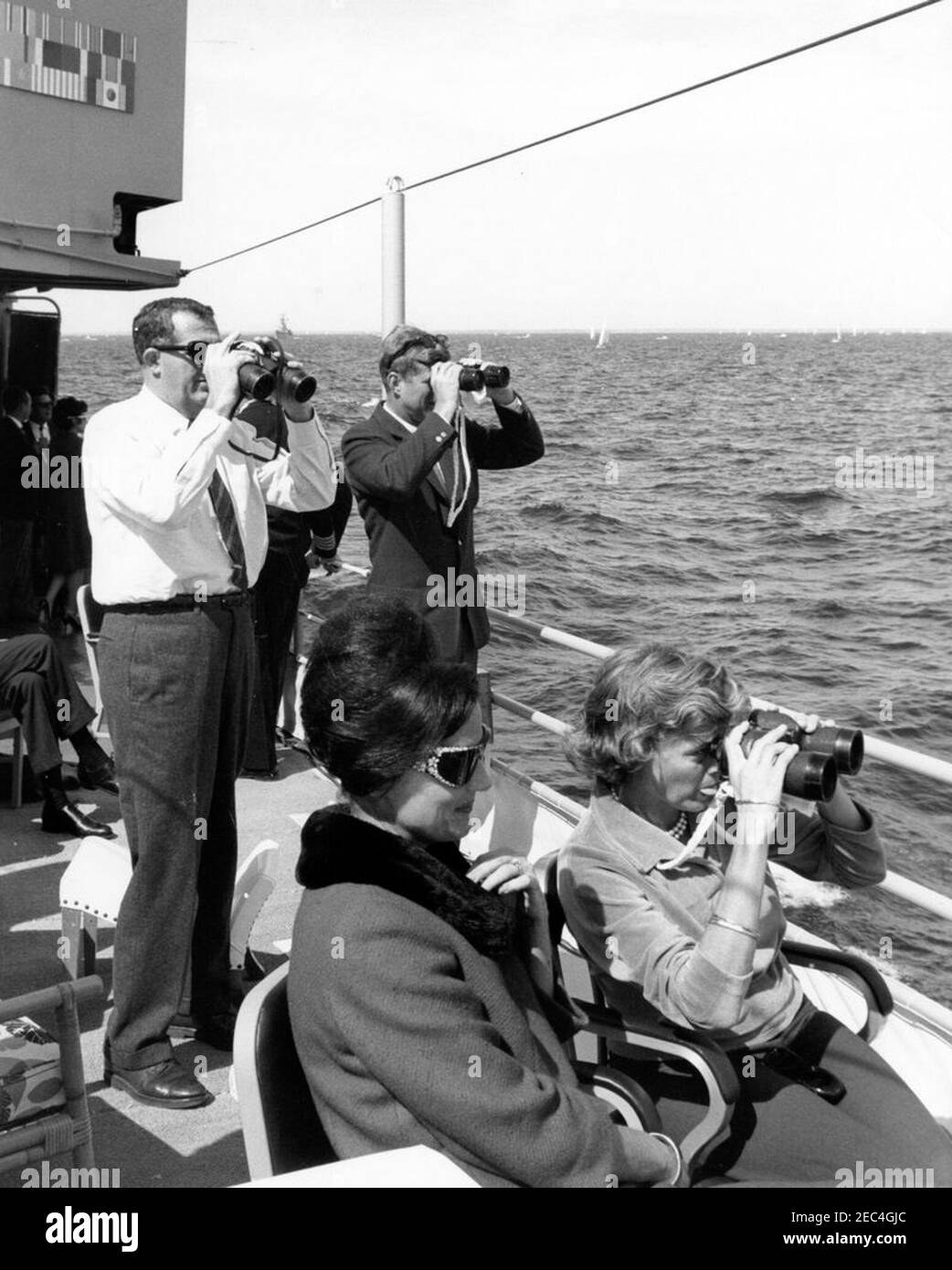 Präsident Kennedy beobachtet das 1st Americau0027s Cup Race. Präsident John F. Kennedy (Blick durch Fernglas) beobachtet das erste Rennen des Cup 1962 Americau0027s von an Bord der USS Joseph P. Kennedy, Jr. auch im Bild: Assistant Secretary of the Treasury, James A. Reed; Julia Ann Shepard (Ehefrau von Naval Aide to the President, Captain Tazewell Shepard). Newport, Rhode Island. Stockfoto