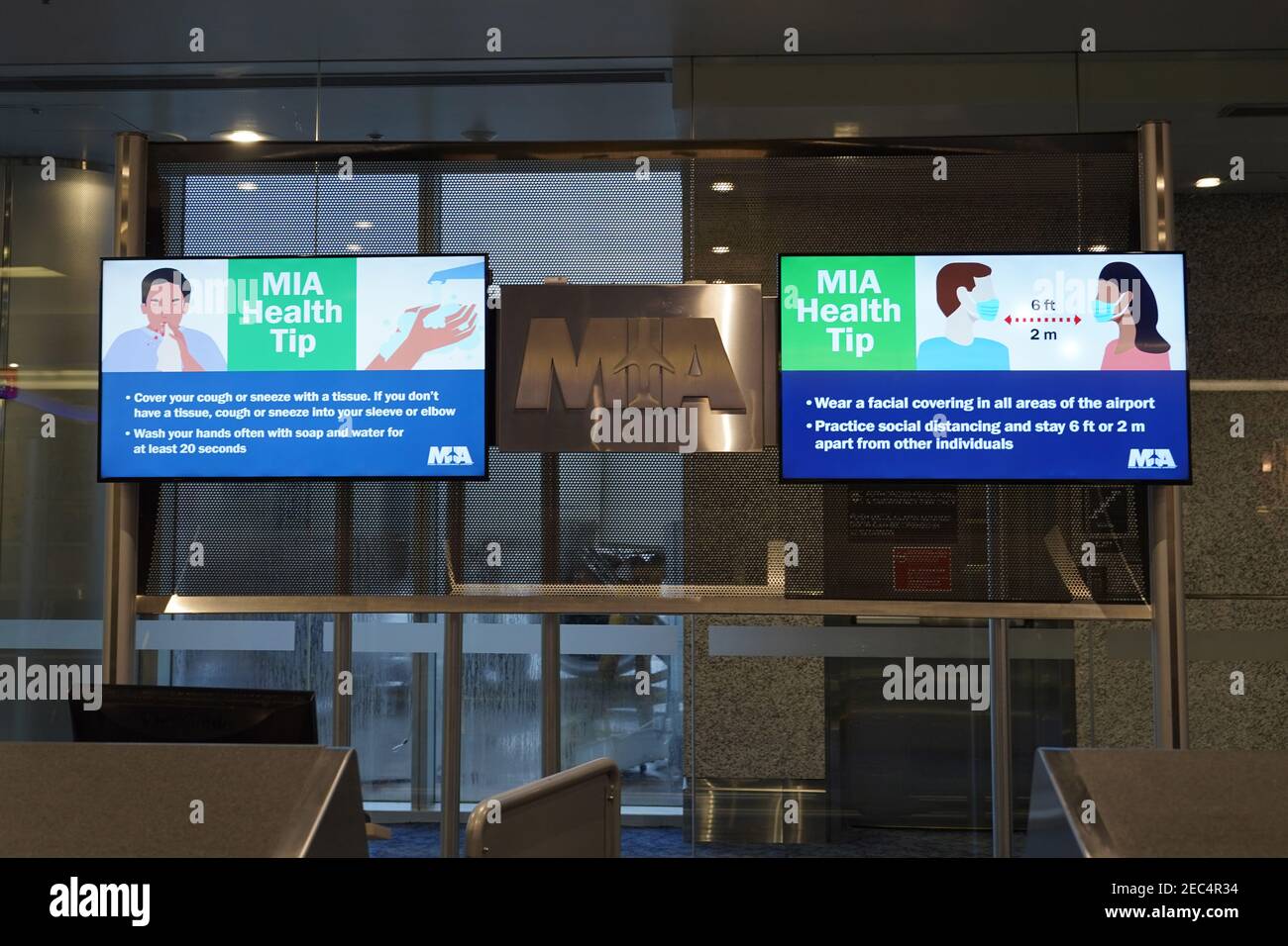 Monitore mit COVID-19 Gesundheitshinweisen im Terminal D des Miami International Airport, Samstag, 13. Februar 2021, in Miami. Stockfoto