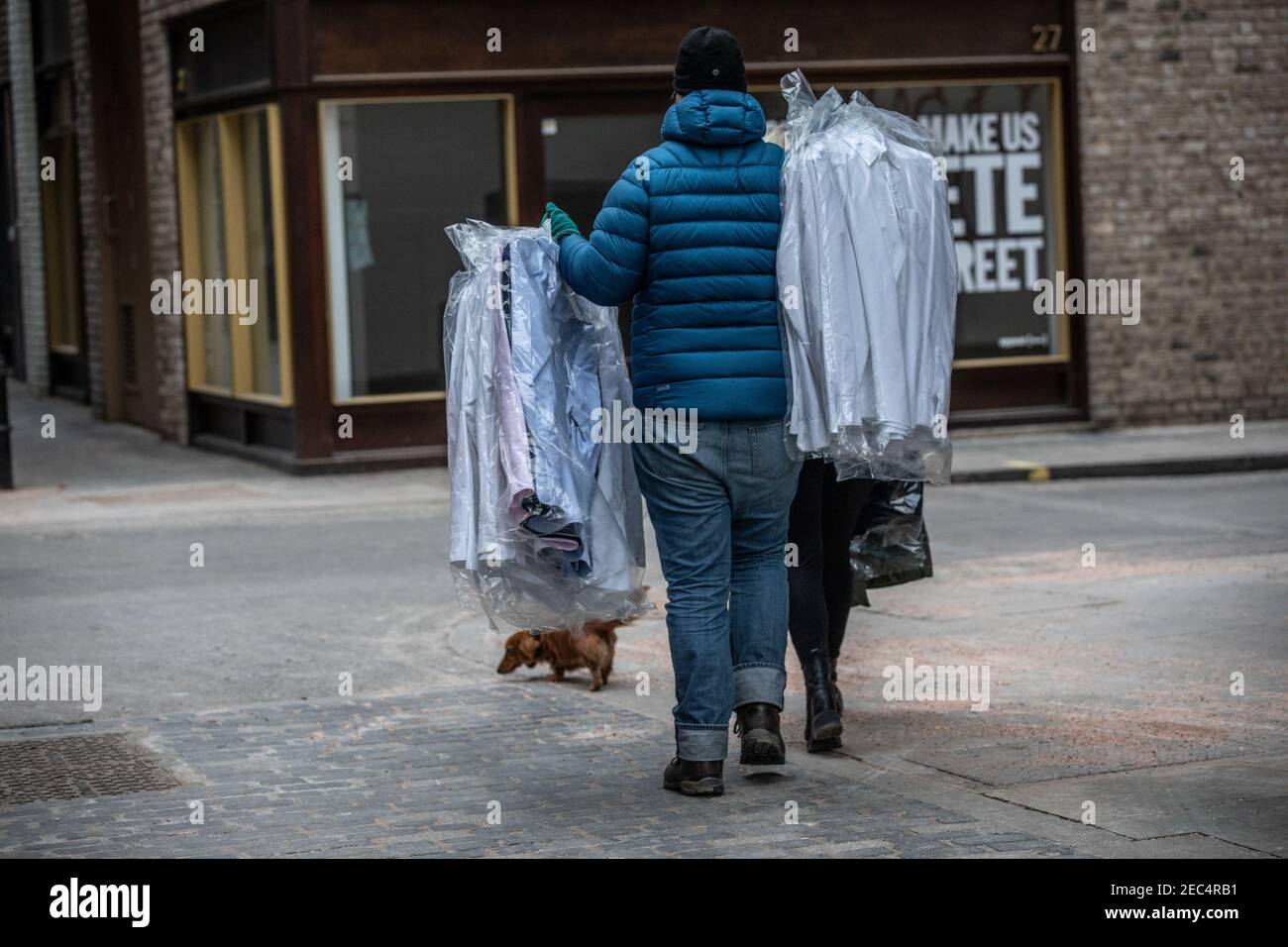 Mann, der seine trocken gereinigten Hemden in einer Vorstadtstraße in London, England, Großbritannien, trägt Stockfoto