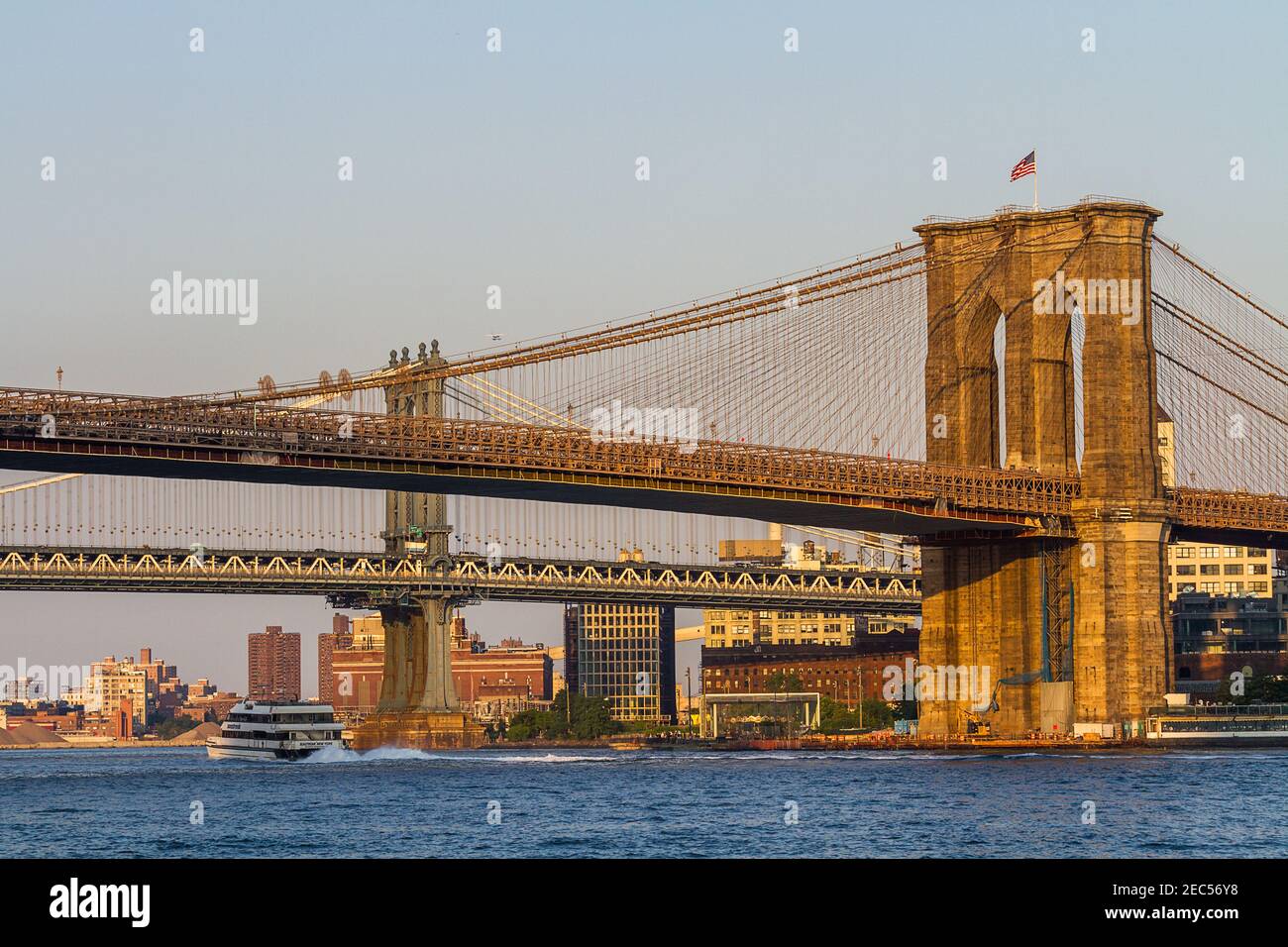 Brooklyn und Manhattan Bridge mit einer Fähre, die unter der vorbeifährt Brücke am Nachmittag Stockfoto