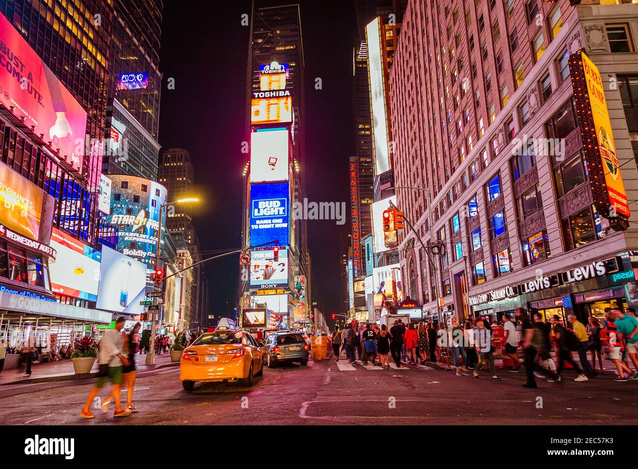 Blick auf den Times Square bei Nacht mit verschwommenen Taxis und Gruppen von Leuten, die herumlaufen Stockfoto