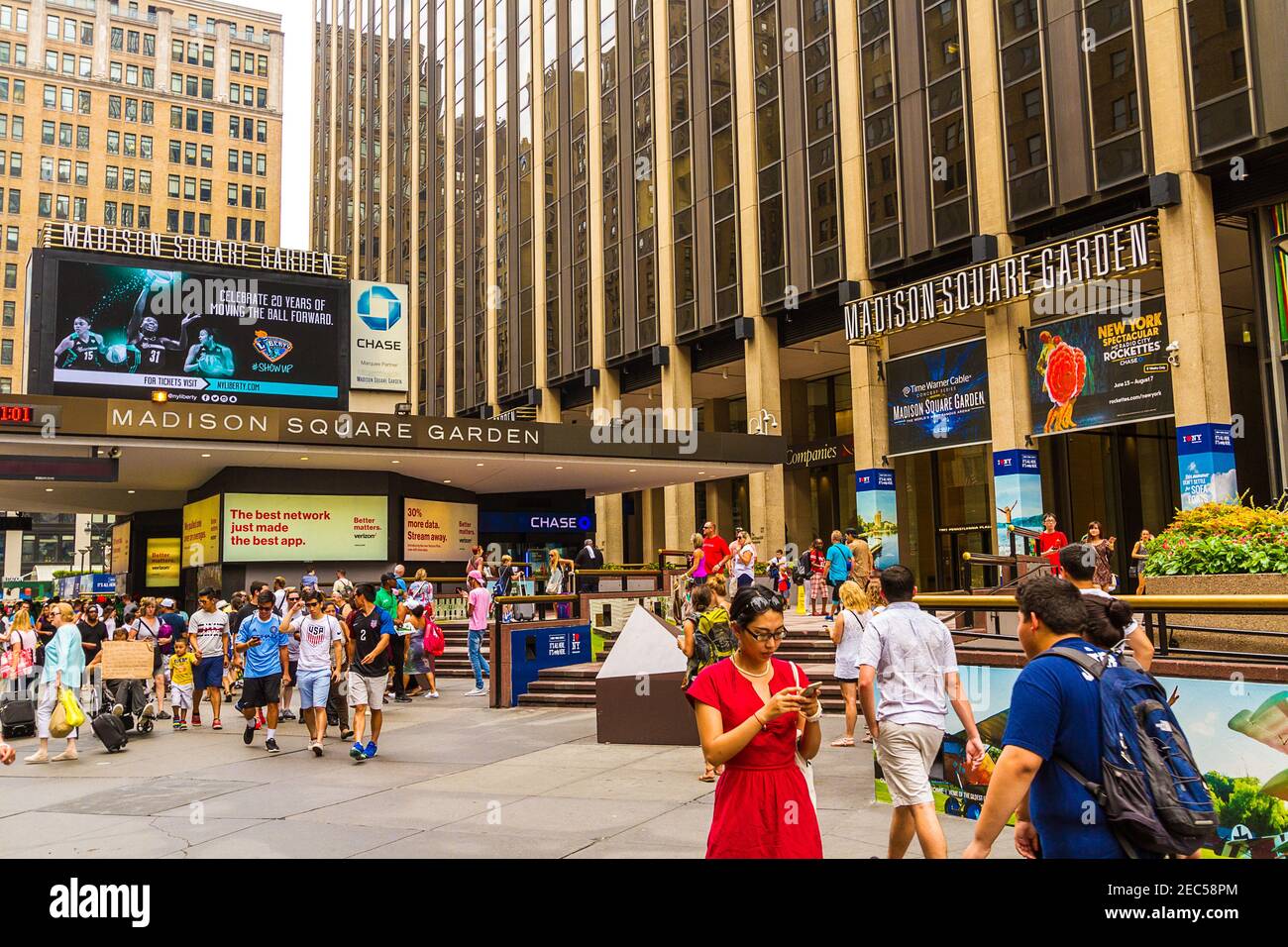 Blick auf den Eingang des Madison Square Garden New York mit Wanderern und einer Frau in Rot Textnachrichten zu Kleidern Stockfoto