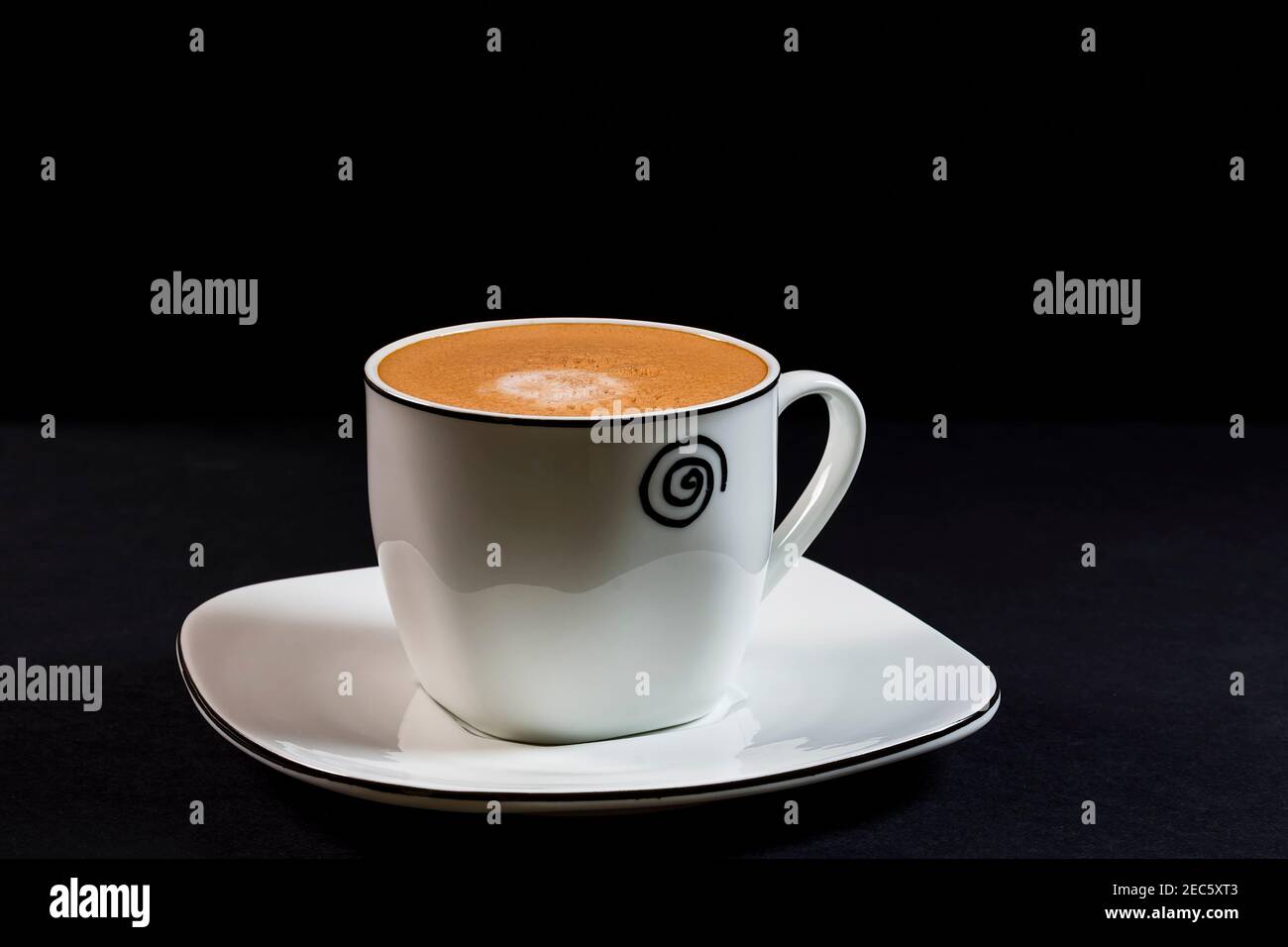 Kaffee mit Milch in Porzellanbecher und Untertasse.das Foto ist eine horizontale Aufnahme, die in einem Studio unter künstlicher Beleuchtung aufgenommen wurde. Stockfoto