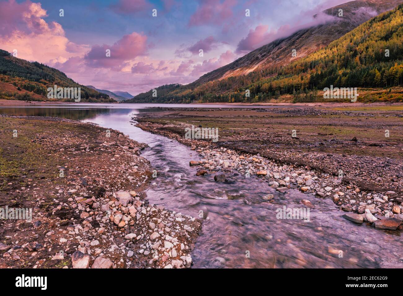 Rosa gefärbte Wolken, wenn die Sonne über dem Coniston-Wasser im Lake District National Park, Cumbria, England, Großbritannien untergeht Stockfoto