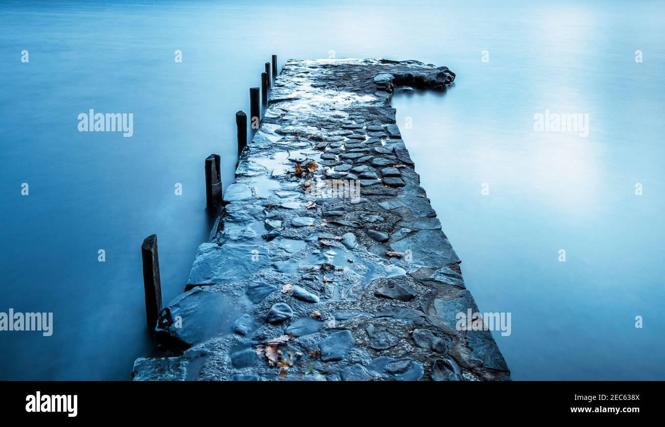 Steinmetzsteg, der sich in die stillen Gewässer des Coniston Water, Lake District National Park, Cumbria, Großbritannien, erstreckt Stockfoto