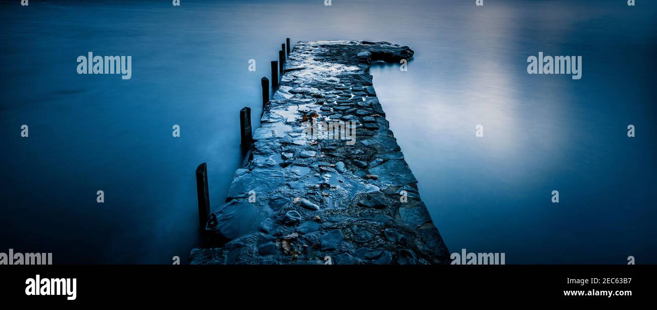 Steinmetzsteg, der sich in die stillen Gewässer des Coniston Water, Lake District National Park, Cumbria, Großbritannien, erstreckt Stockfoto