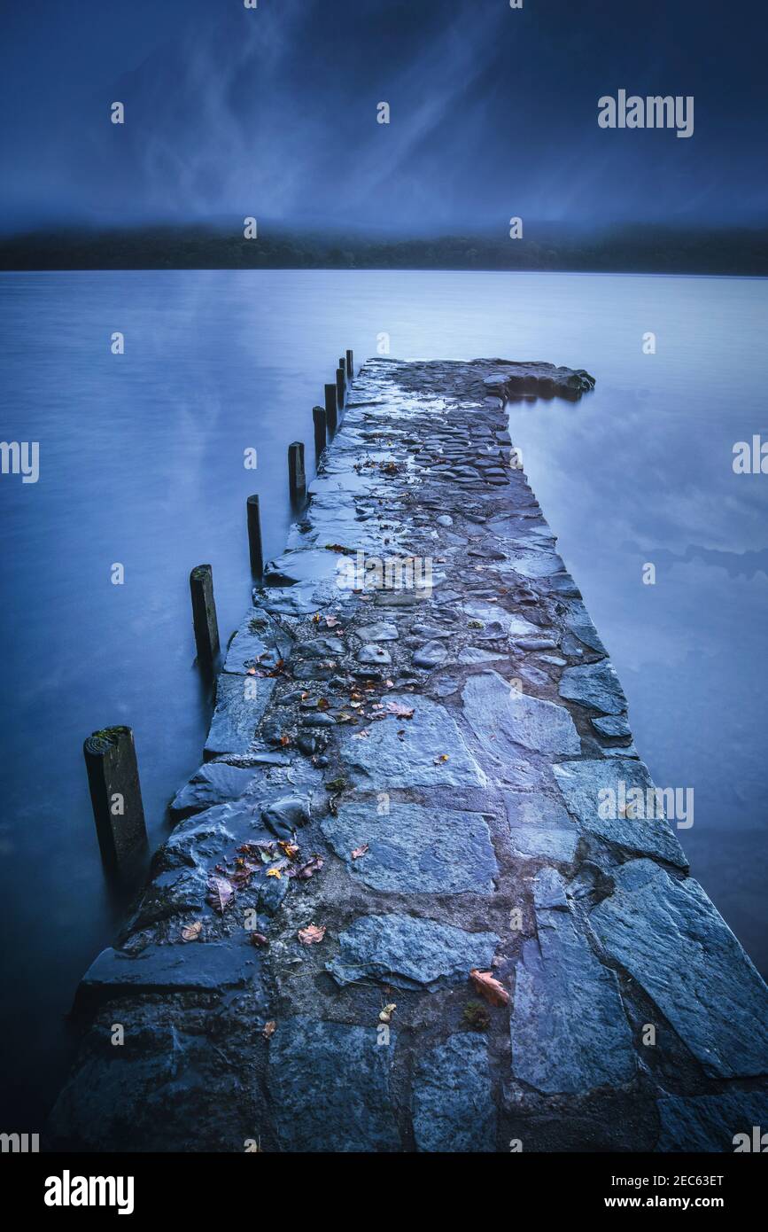 Steinmetzsteg, der sich in die stillen Gewässer des Coniston Water, Lake District National Park, Cumbria, Großbritannien, erstreckt Stockfoto