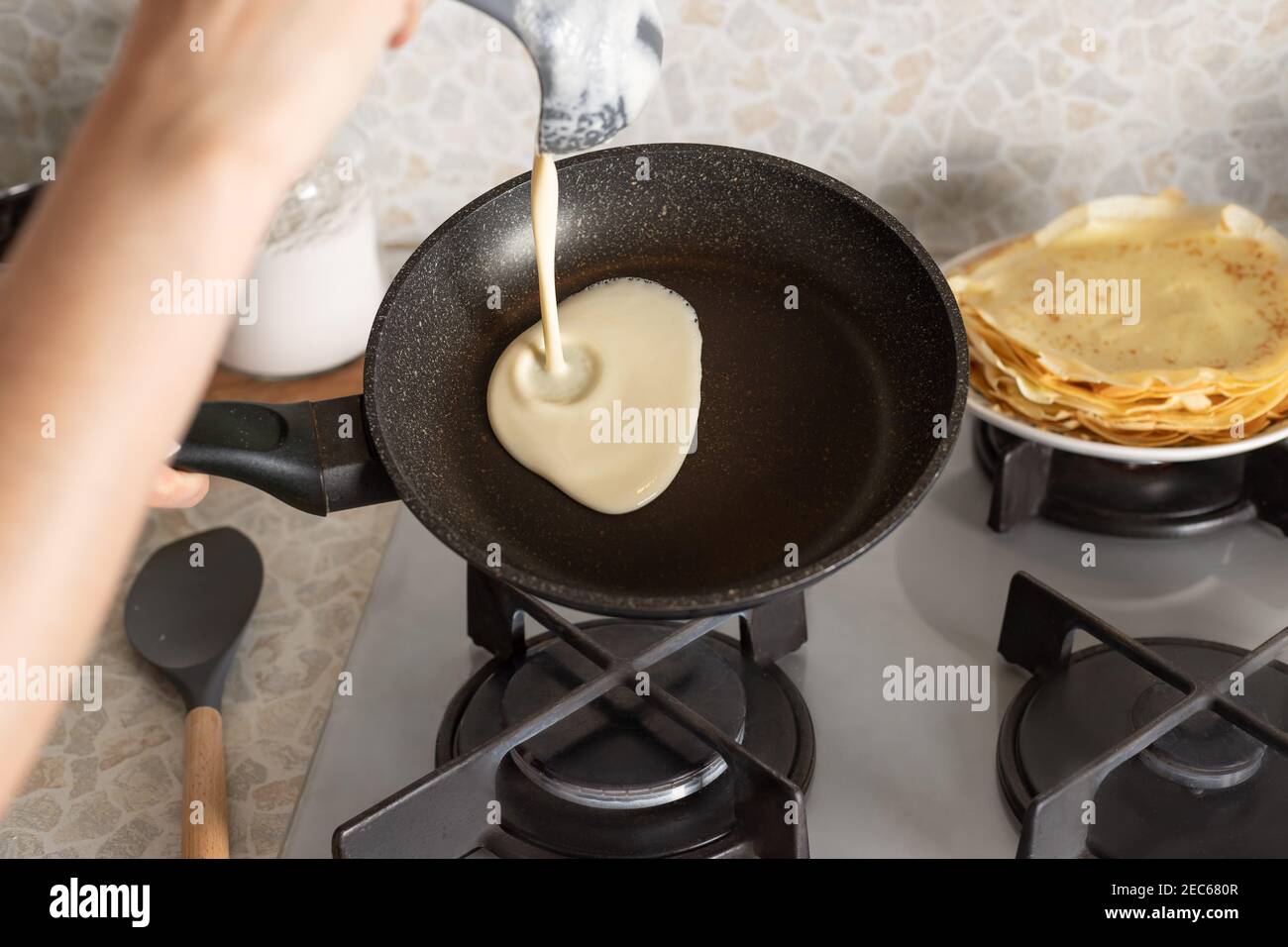 Person Kochen dünne Pfannkuchen auf Bratpfanne in der Küche Stockfoto