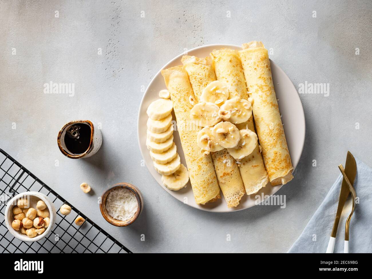 Gerollte Pfannkuchen, Crepes serviert mit Banane, Nüsse, Kokosnuss Stockfoto
