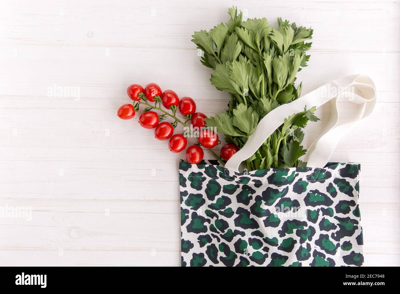 Eco Einkaufstasche im trendigen Leopardenmuster-Print mit frischem Bio-Gemüse und Salat auf weißem Holzhintergrund, Top View, Flat Lay Stockfoto