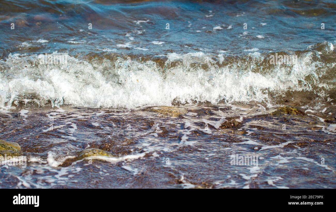 Kaltes blaues Meerwasser surft über der Küste. Kühle Meereswelle spritzt über die Küste. Starke ozeanische Strömung. Minimale Meereslandschaft für Reisehintergrund. Gefährlich Stockfoto