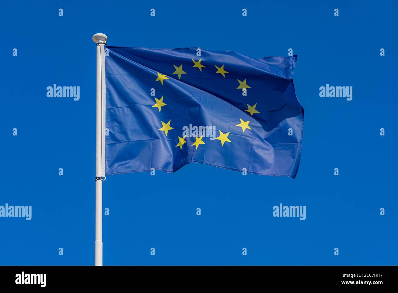 Einzelne europäische Flagge mit zwölf gelben Sternen winken im Wind auf blauem Himmel Hintergrund, Nahaufnahme. EU-Flagge Stockfoto