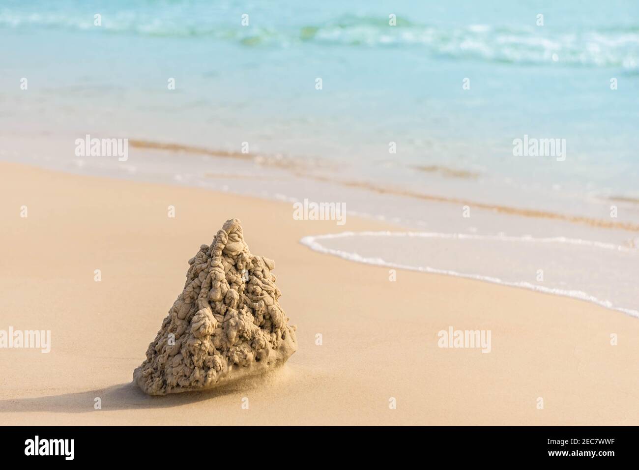 Kleine Sandburg am Sandstrand in der Nähe von wehenden türkisfarbenen Meer. Spielen mit Sand und Sandburg am Meer bauen. Stockfoto