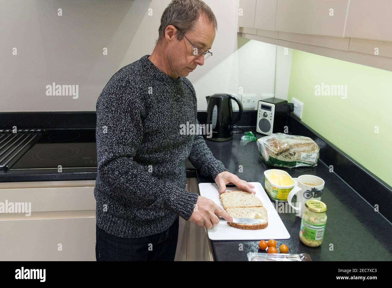 Sandwich machen Rentner männlich macht ein Corned Beef und Tomate Sandwich zu Hause in der Küche während der Sperre 2020. Ein Selbstbild von sieben aufgenommen. Stockfoto