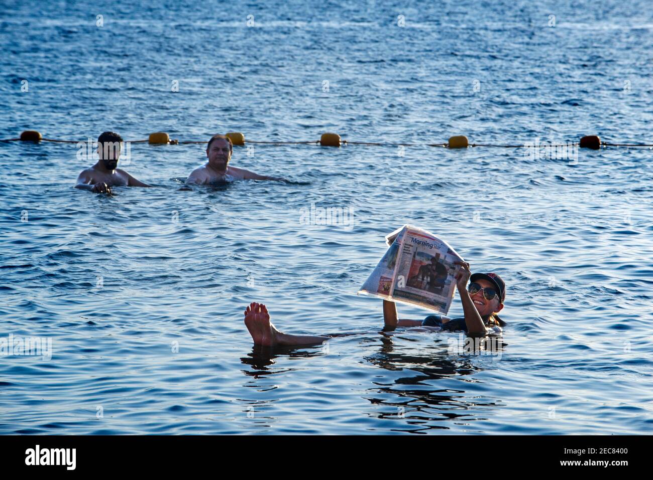 Junge Frau schwebt und Lesen einer Zeitschrift im Toten Meer, Jordanien Stockfoto