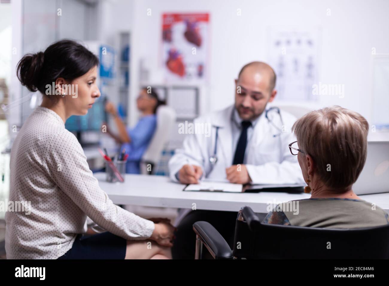 Doughter und behinderte Mutter im Rollstuhl sitzend im Gespräch mit dem Arzt während der Konsultation. Praktiker Fragen stellen, um Patienten füllen Krankheitsgeschichte Form reifen, verschreiben Behandlung Stockfoto