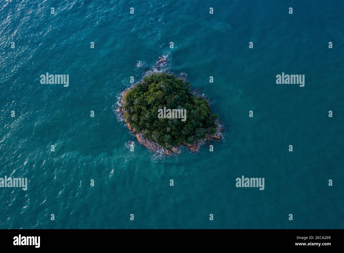 Luftaufnahme einer kleinen felsigen Insel mit Grünflächen Mitten im türkisfarbenen Meer Stockfoto